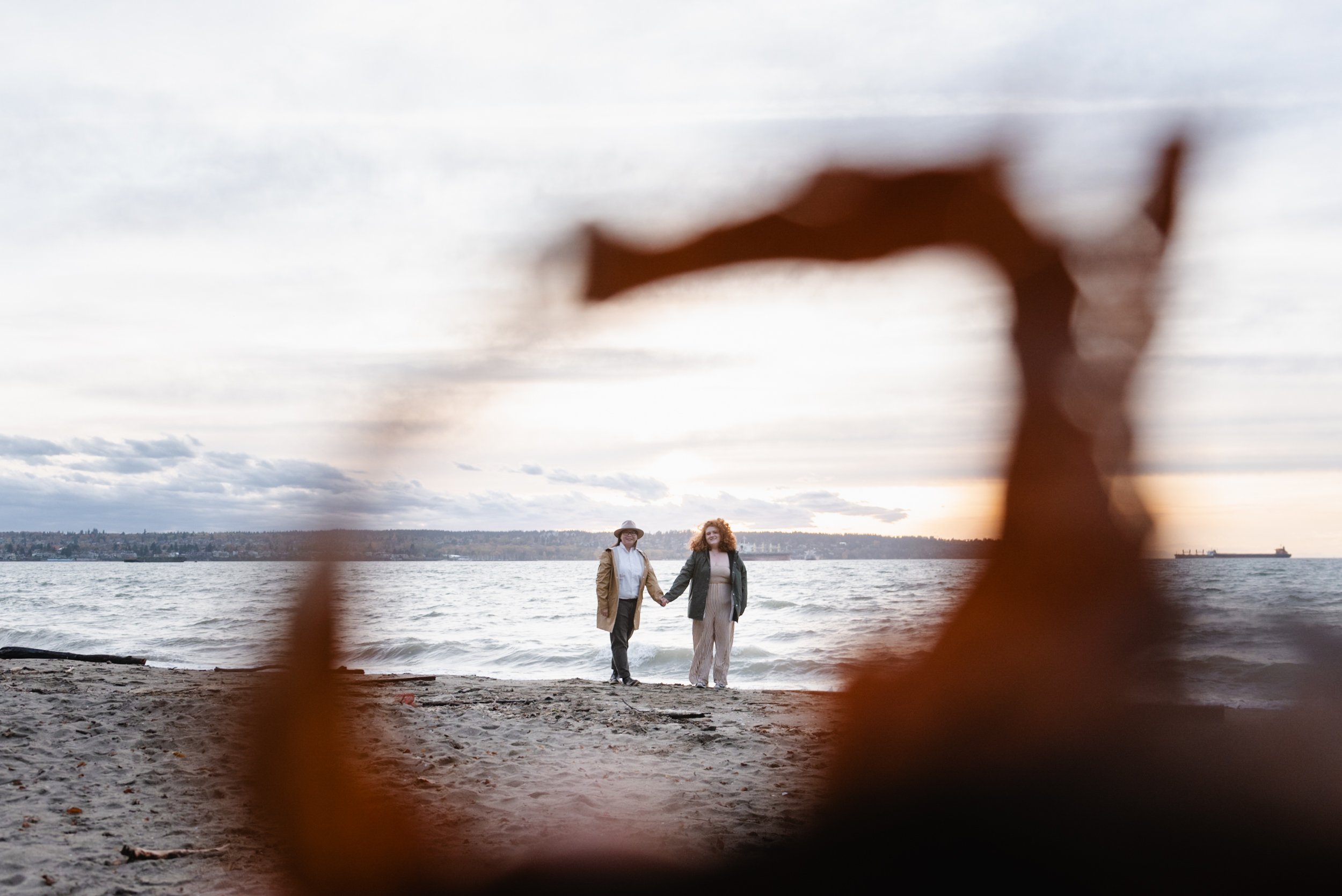 Wide shot of couple holding hands at Stanley Park's Second Beach