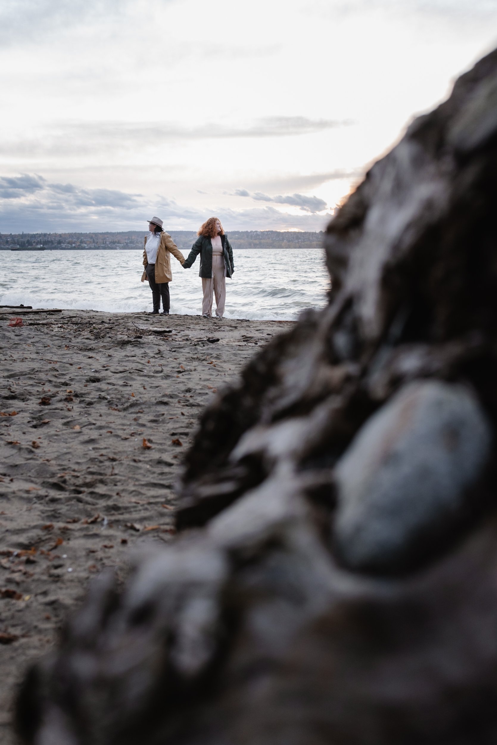 Wide shot of couple holding hands at Stanley Park's Second Beach