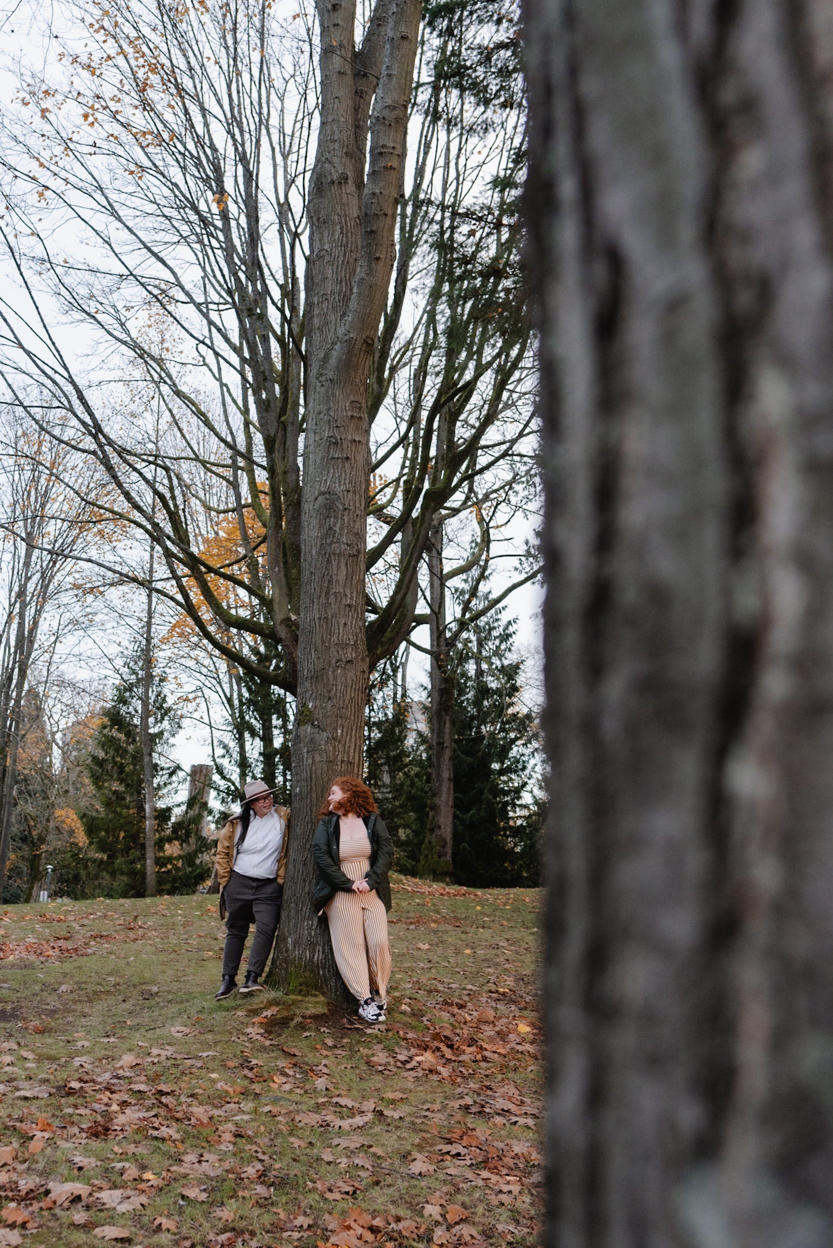 Couple leaning against a tree at Stanley Park looking at each other