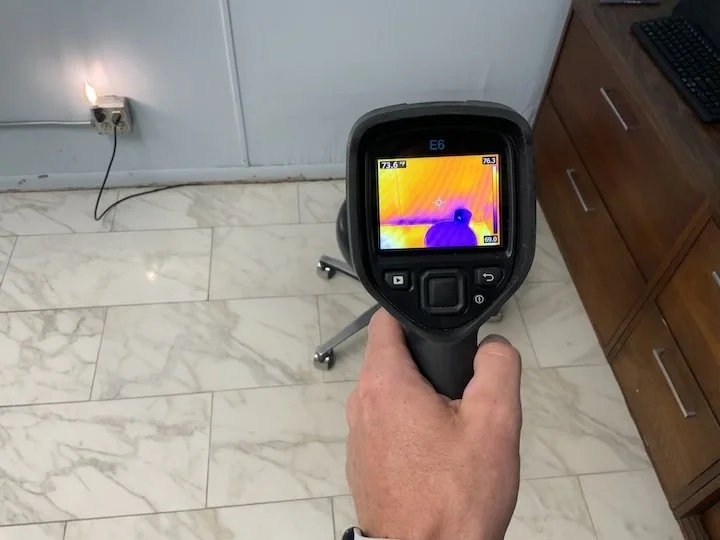 Inspector using thermal camera on commercial roof with Houston skyline