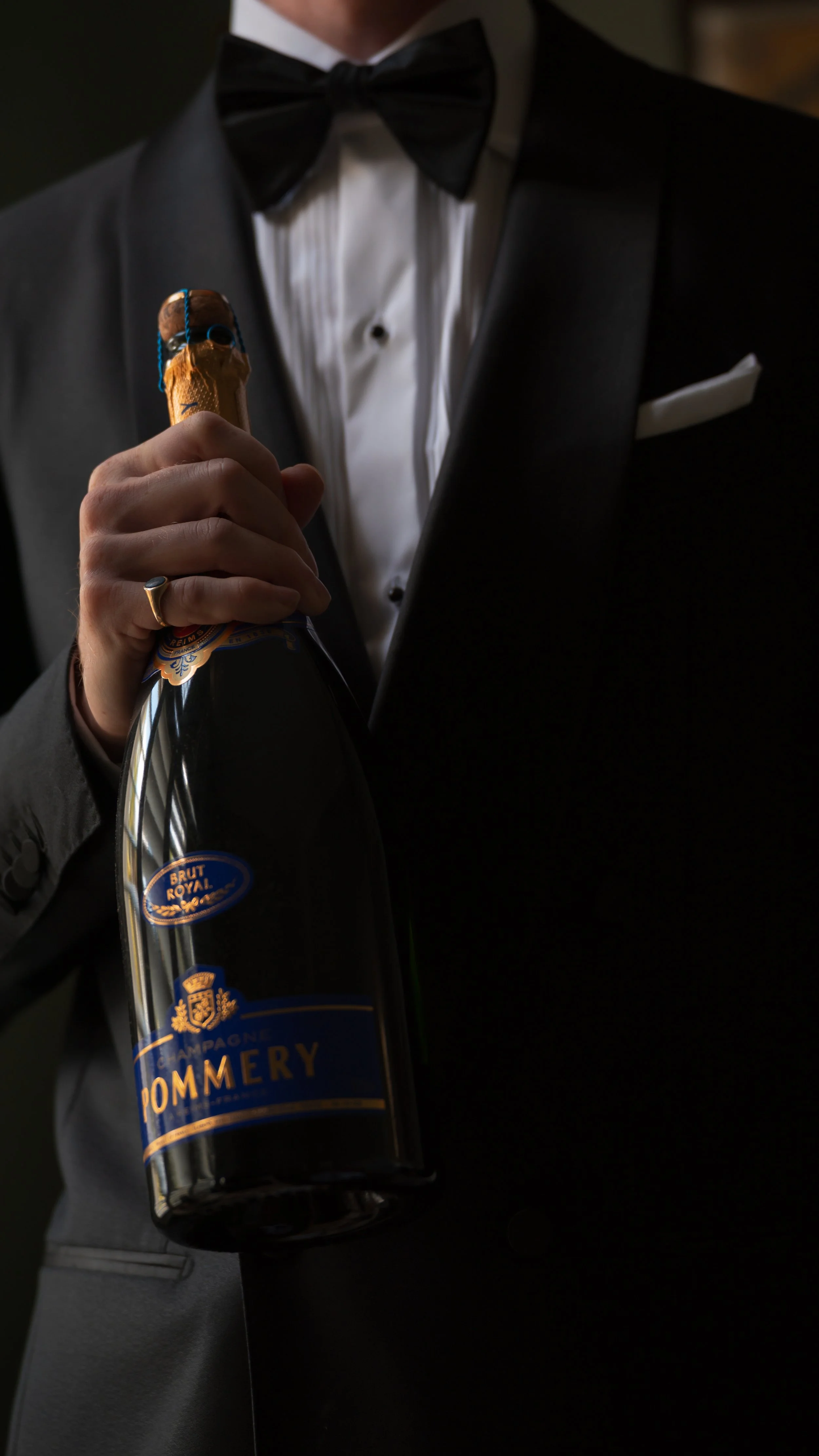 A man in a tuxedo holding a bottle of Dommery champagne.
