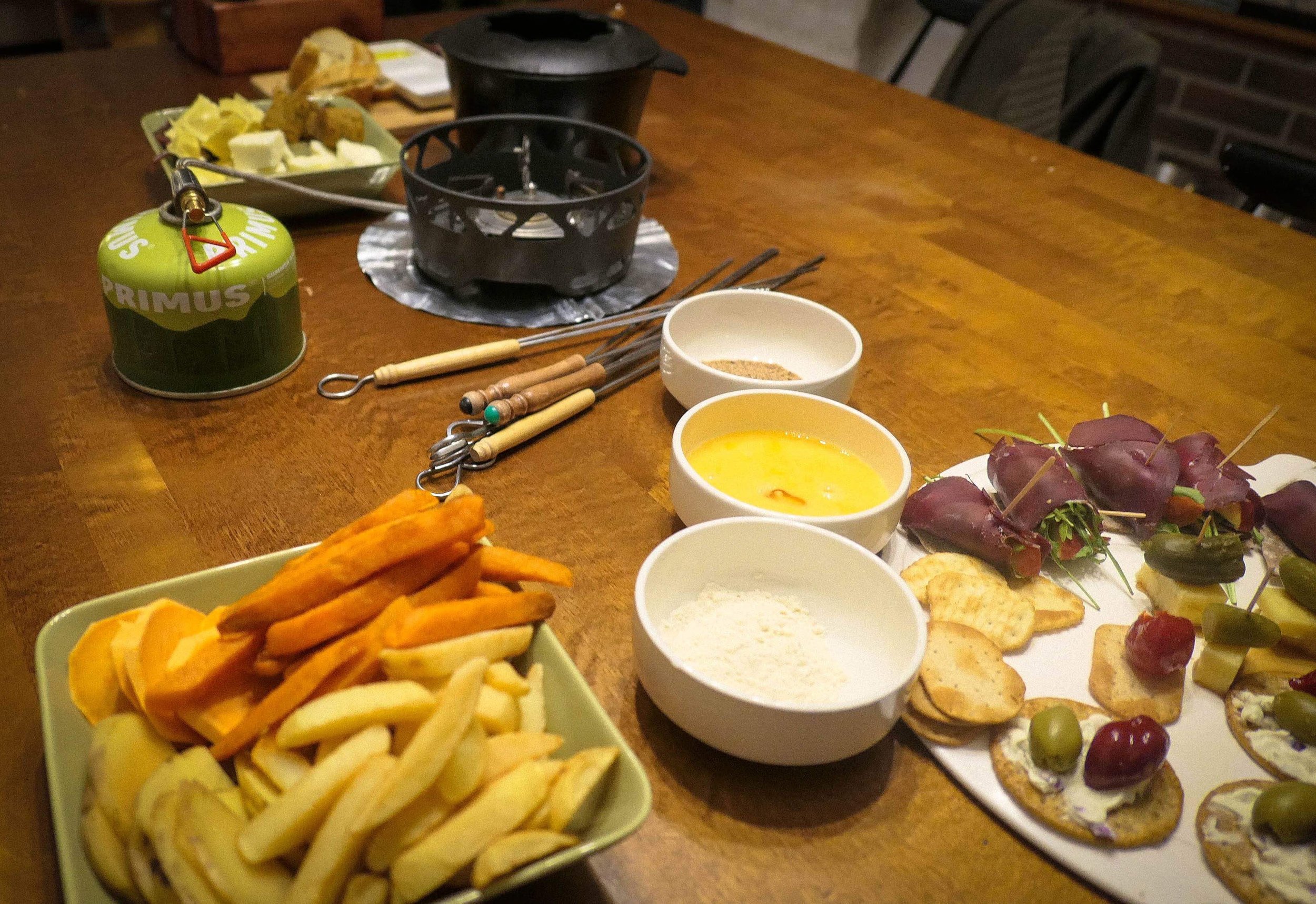 Kotini ruokapöydällä fondue-pataa lämmitetään retkikeittimellä ja testissä on mahdollisia juttuun tulevia herkkuja.