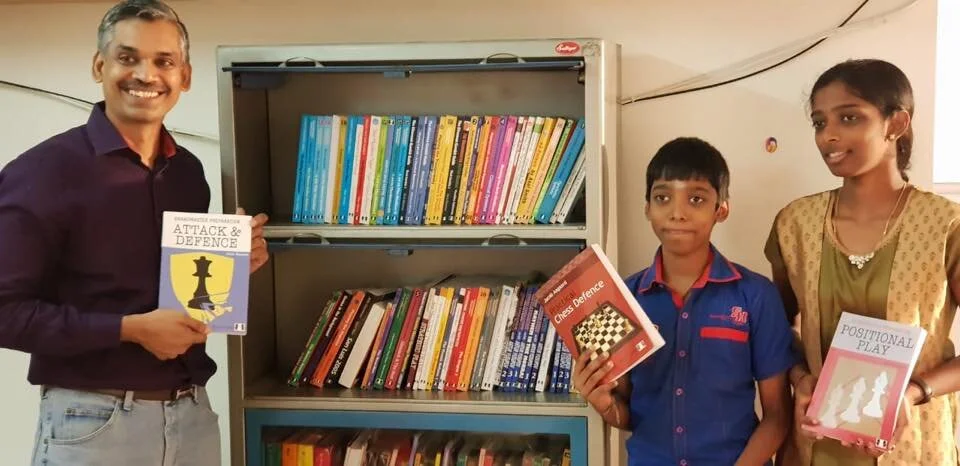 GM Ramesh shows off some of his Quality Chess books, with his star students GM Praggnanandhaa and WIM Vaishali (photo courtesy of GM Ramesh)