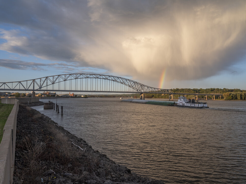 The “Michael A. Nadicksbernd” of American Commercial Lines gets a rainbow as it heads upstream toward the Julien Dubuque Bridge, Dubuque, Iowa