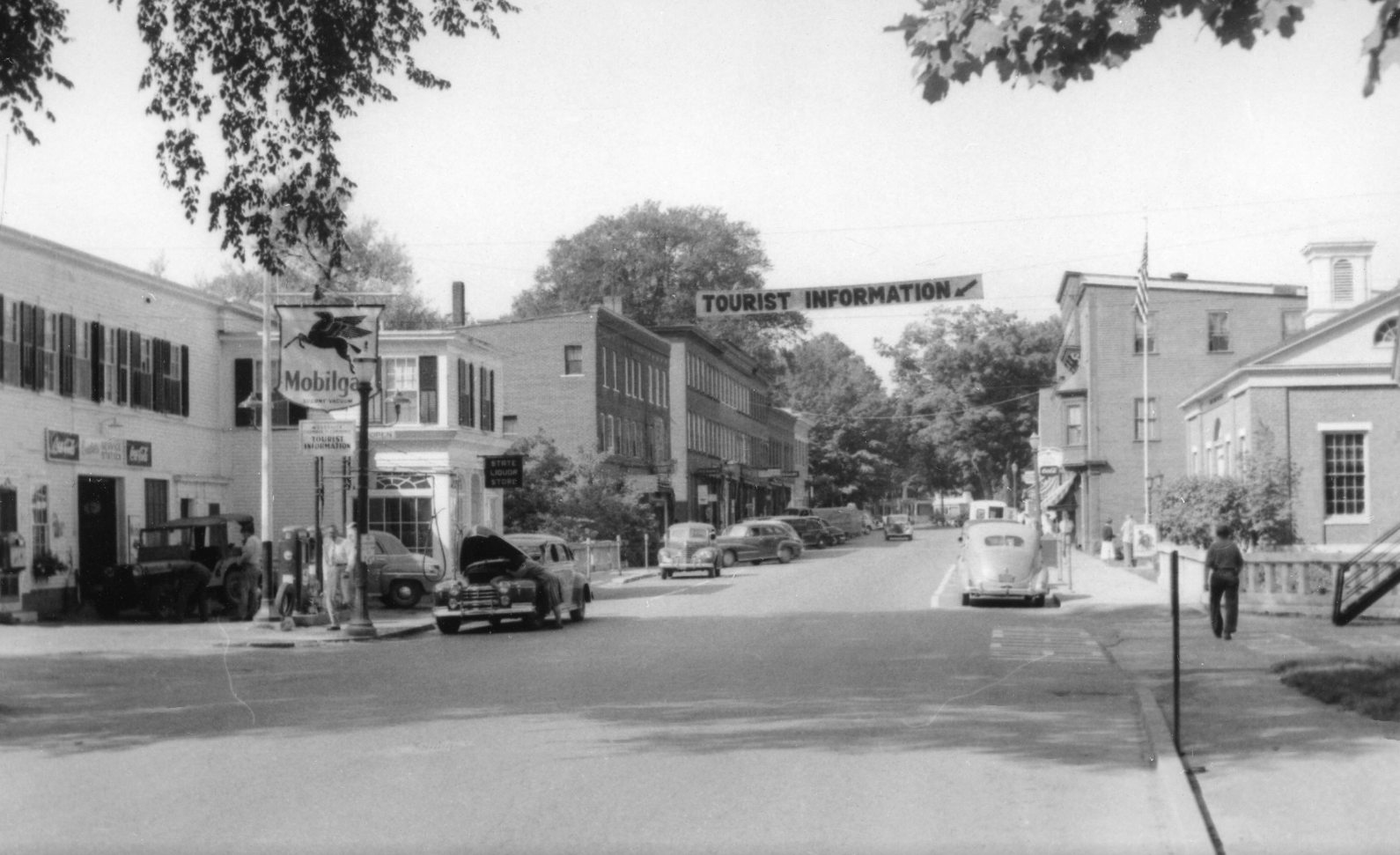 From the Mobilegas station, you can see a "Tourist Information" banner across the street. It is an indication of Woodstock's expanding tourist economy in the early 20th century.