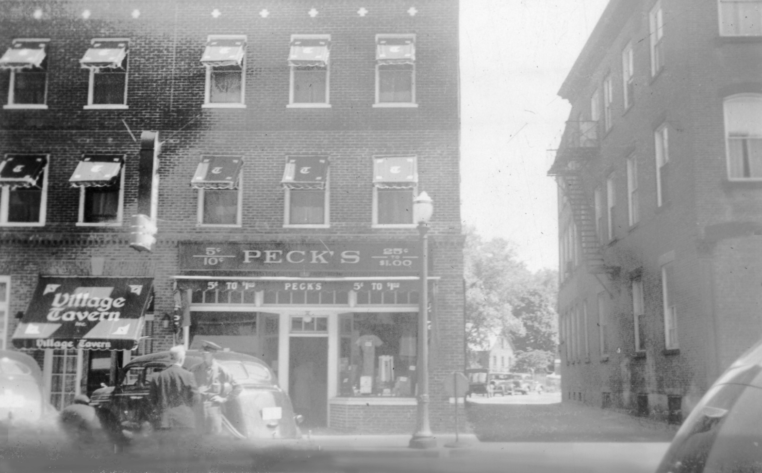 Continuing down the street, you can see by the time this photo was taken, a part of the building that had been a restaurant is now Peck's 5¢ to $1.00 store.