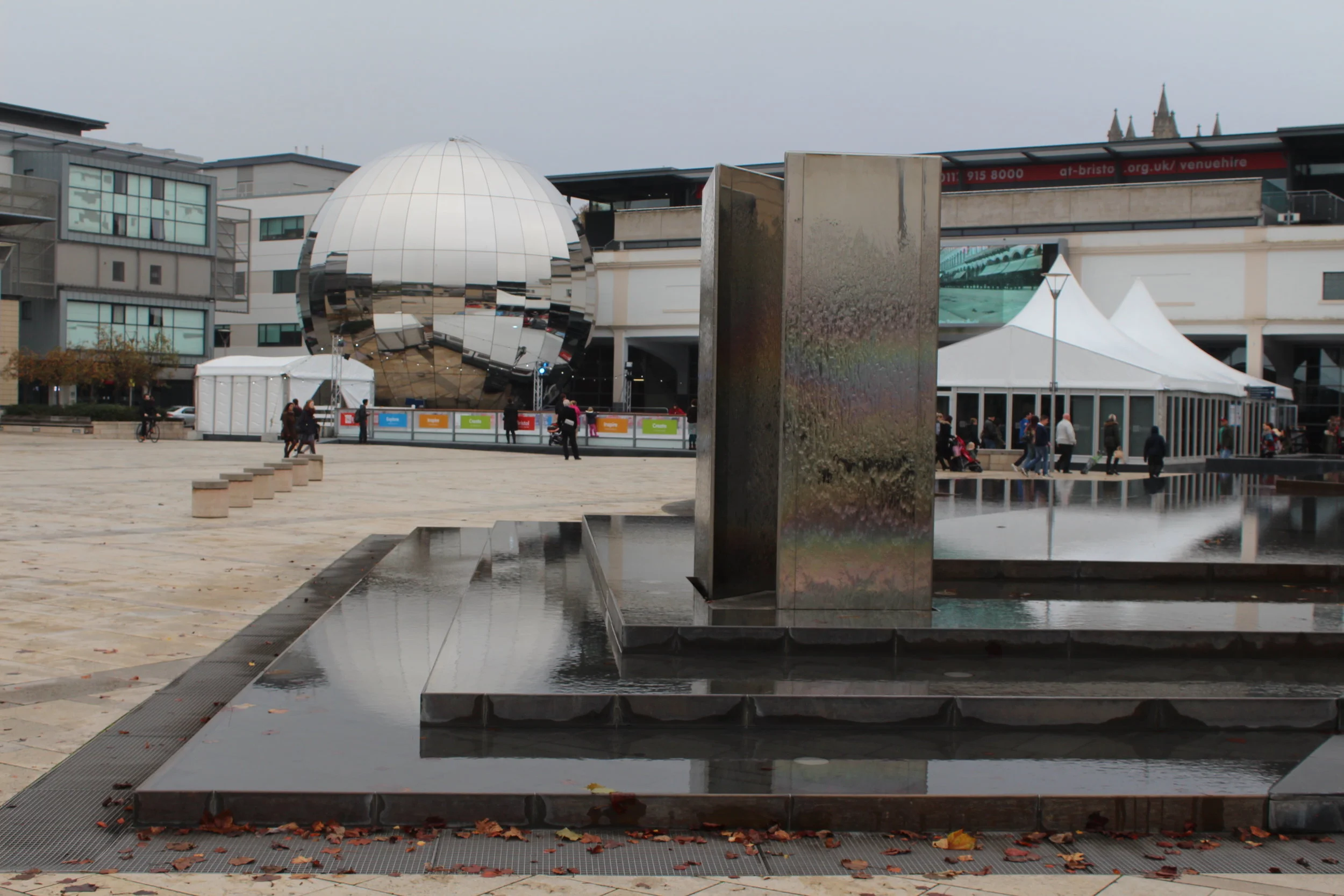 A water fountain disguised as steps, in front of the Planetarium (mirrored ball) and an ice rin