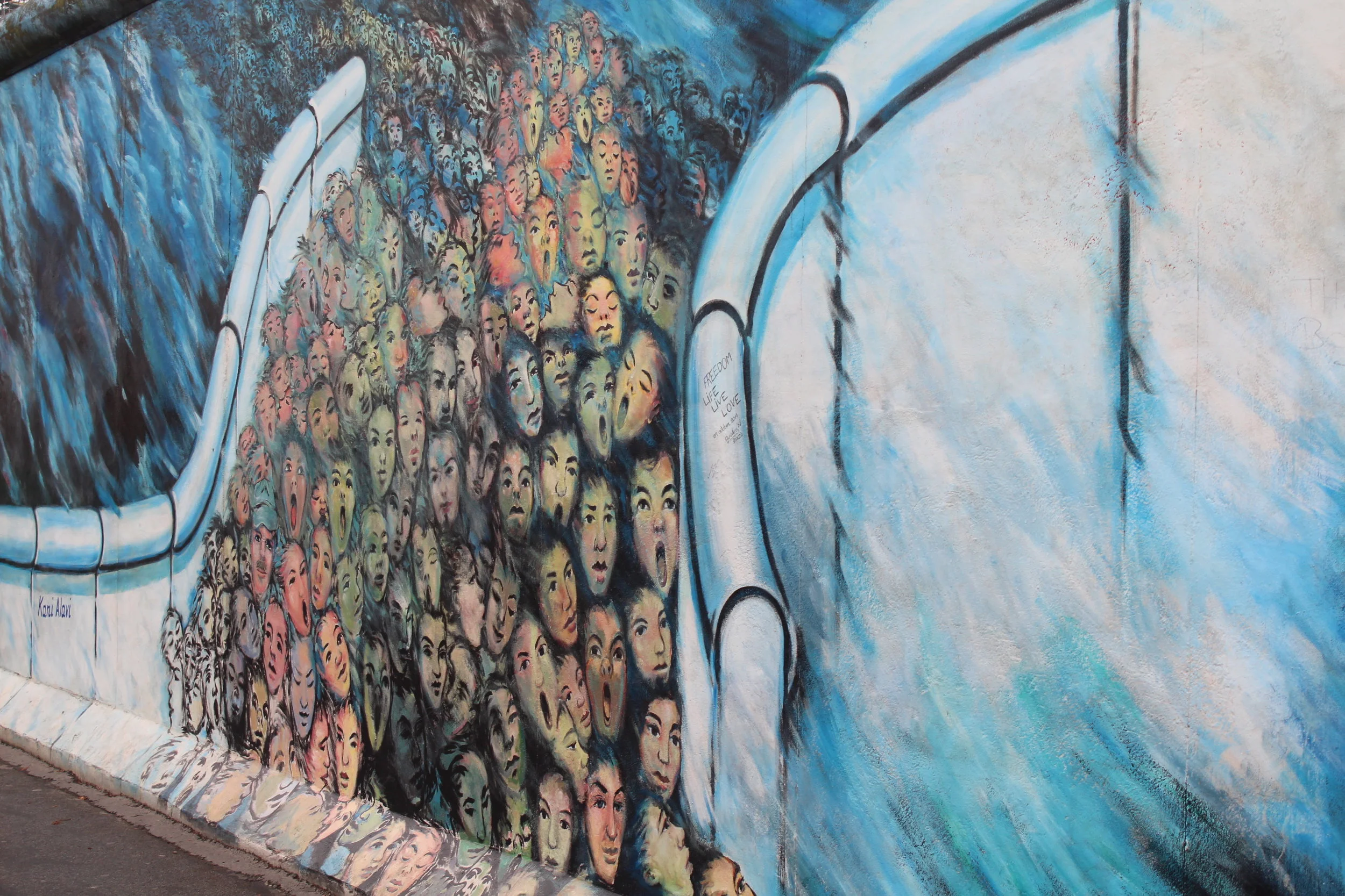 Kani Alavi, who moved from Iran to West Berlinin 1980, used to live four metres away from the wall, next to Checkpoint Charlie. This painting, "Es geschah im November", shows thousands of insecure and sad faces of East Berliner's crossing over to the west when the wall came down. He often speaks out about his surprise when he looked closer at the expressions from East Berliners and found fear rather than excitement.