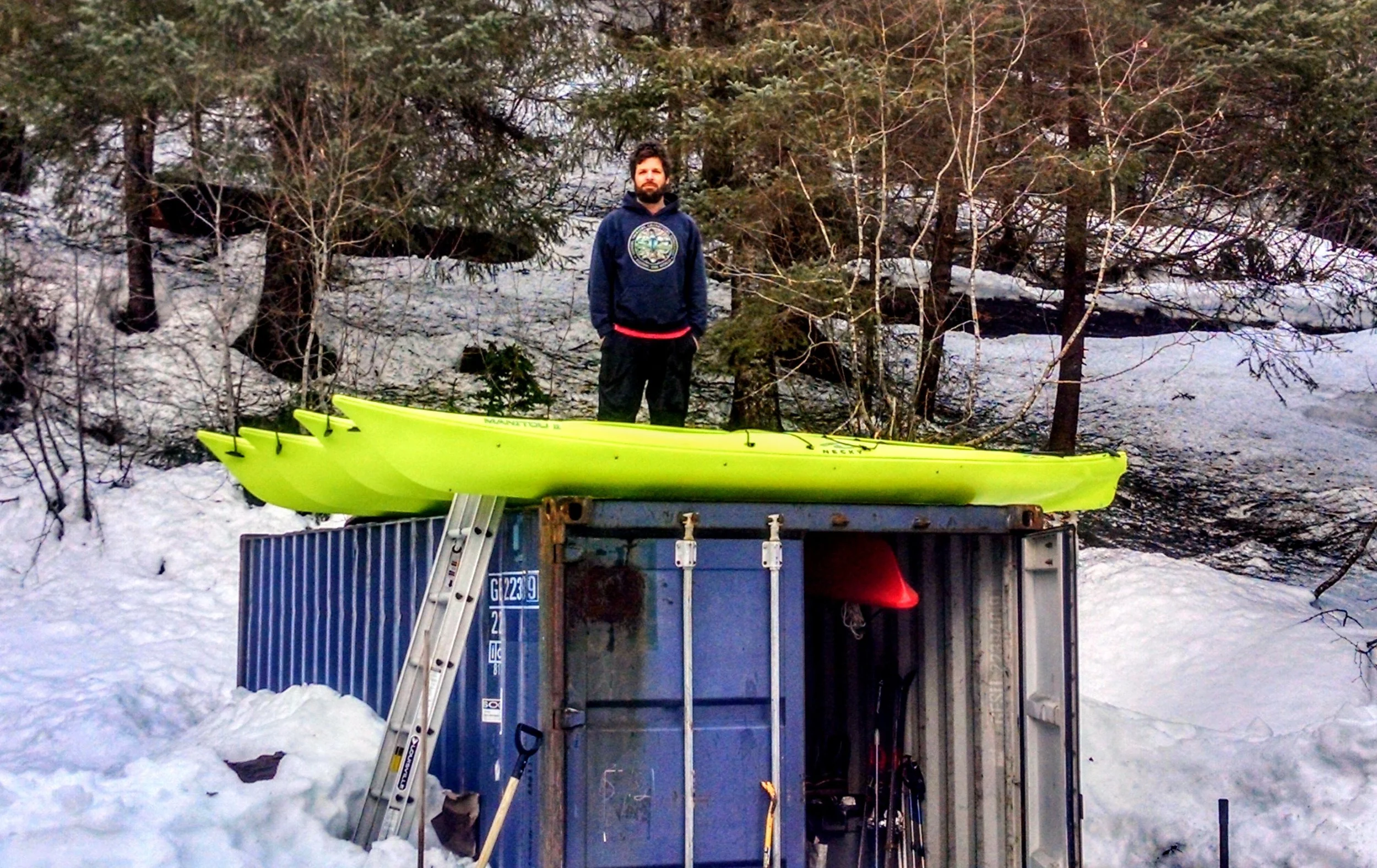 Jason with the new kayaks on top of our storage conex. Our other three kayaks are hanging from the ceiling inside.