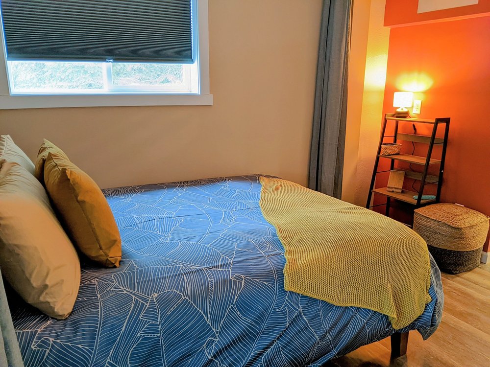 Downstairs bedroom area with shelving and a poof.