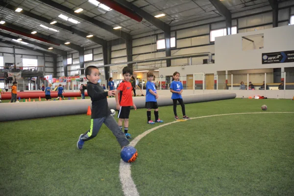 Boy Runs with Soccer Ball While Students Watch