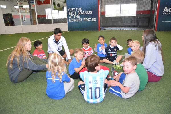Soccer Cubs Sit in a Circle with the Coaches