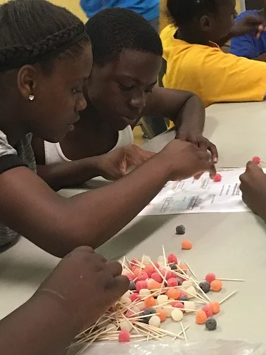 STUDENTS AT FLATWOOD COMMUNITY CENTER STUDYING BRIDGE DESIGNS TO REPLICATE IN THEIR OWN STRUCTURE.