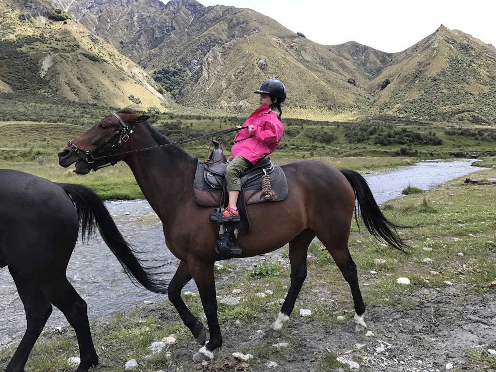 Anais pulling on Tigger's rein to get him to slow down.