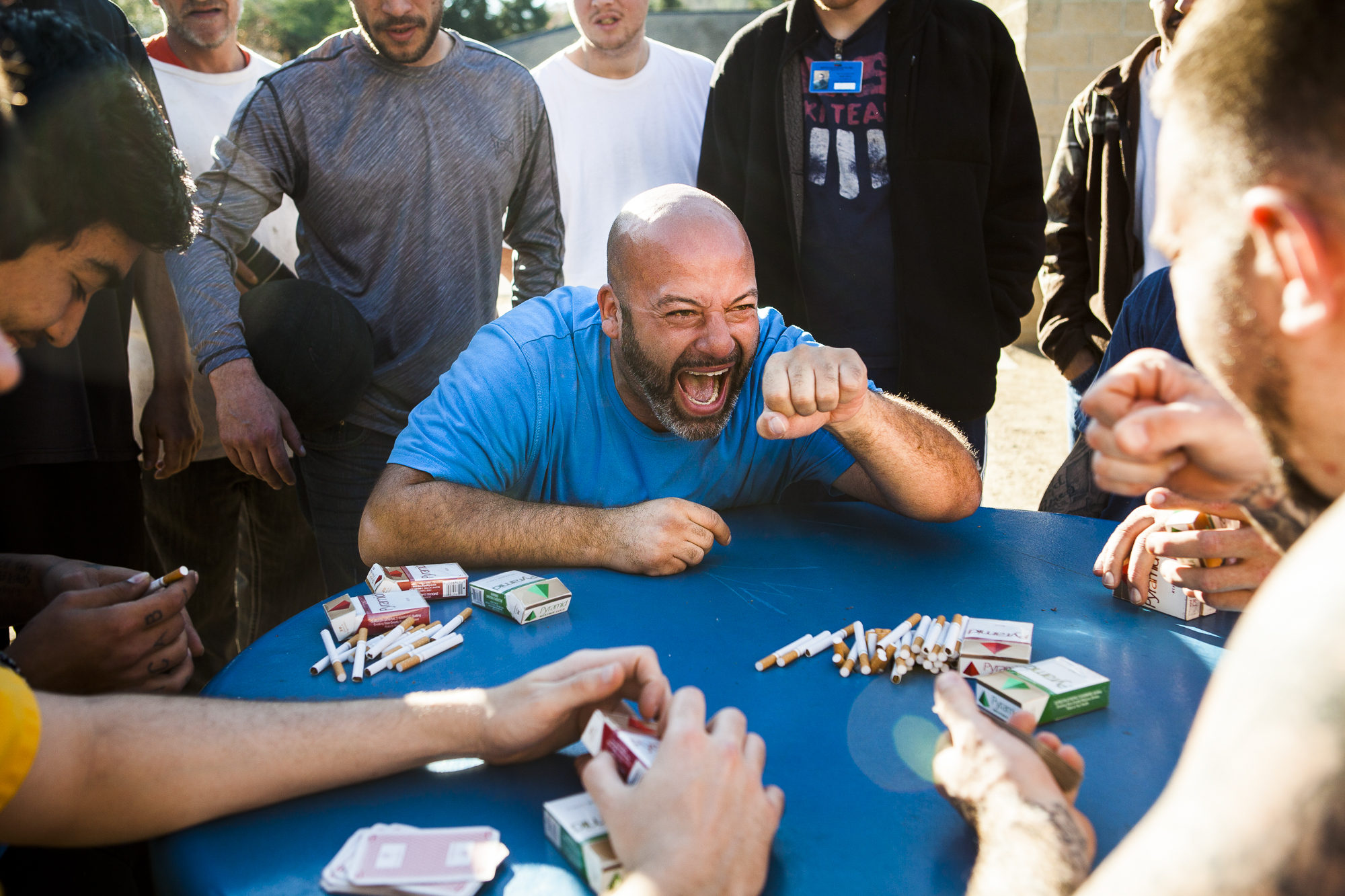 Aaron Kline celebrates a win with Jason Cook as they gamble for a pool of cigarettes at SEPTA Correctional Facility in Nelsonville, Ohio. Chris Streeter, far left, ended up winning the pool of cigarettes, a total of 11 packs, and plans to use them to trade for a “pick and poke” (tattoo).