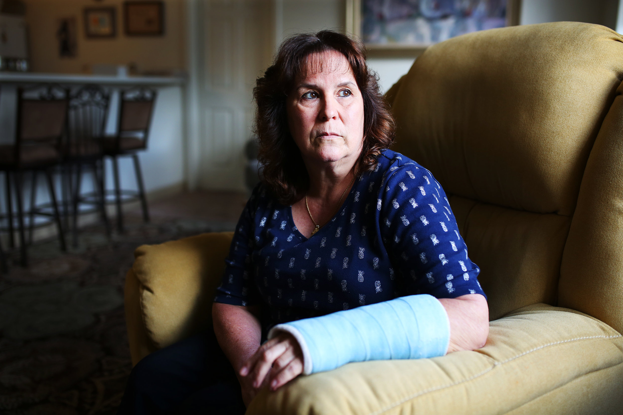 Bernadette Coughlin sits in her living for a portrait nearly one month after she fell and broke her wrist while at work. After the fall, Bernadette was required to take a drug test and her occasional recreational marijuana use led to a positive result. She then lost her job.