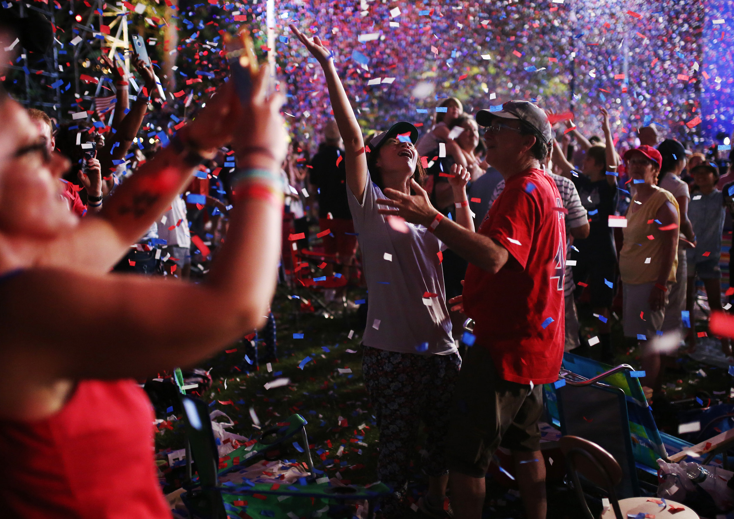People celebrate in the confetti during the Boston Pops Fireworks Spectacular. Despite the heat; "a large crowd came out to celebrate one of the country’s largest and oldest public Fourth-of-July events that took place on the Esplanade.