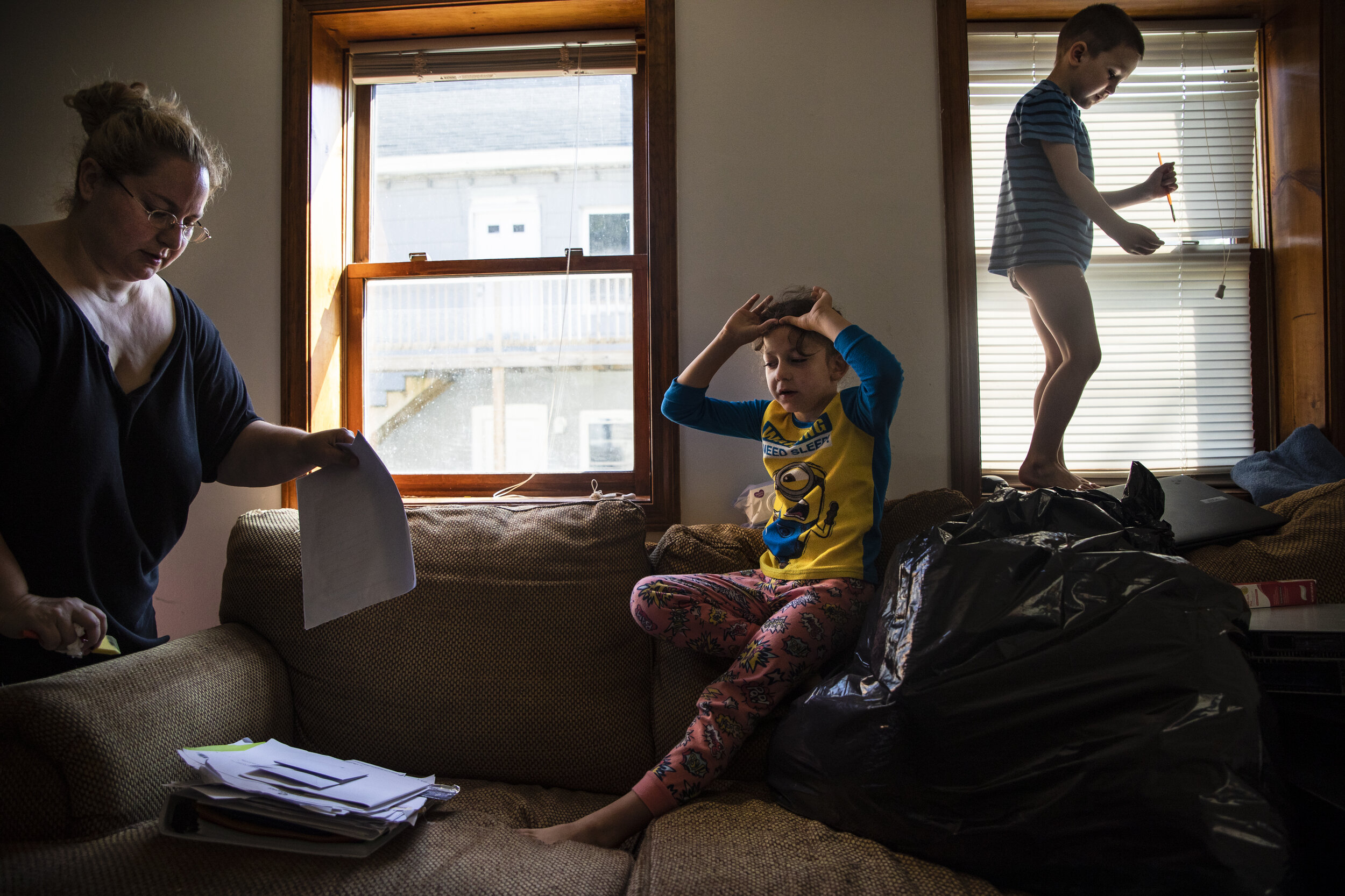 Mariah LeMieux-Lupien organizes paperwork while Evan, center, and Dylan play on the couch. "You just try and do everything right and then 'pftt', you're out," says Mariah, while sorting through her pa