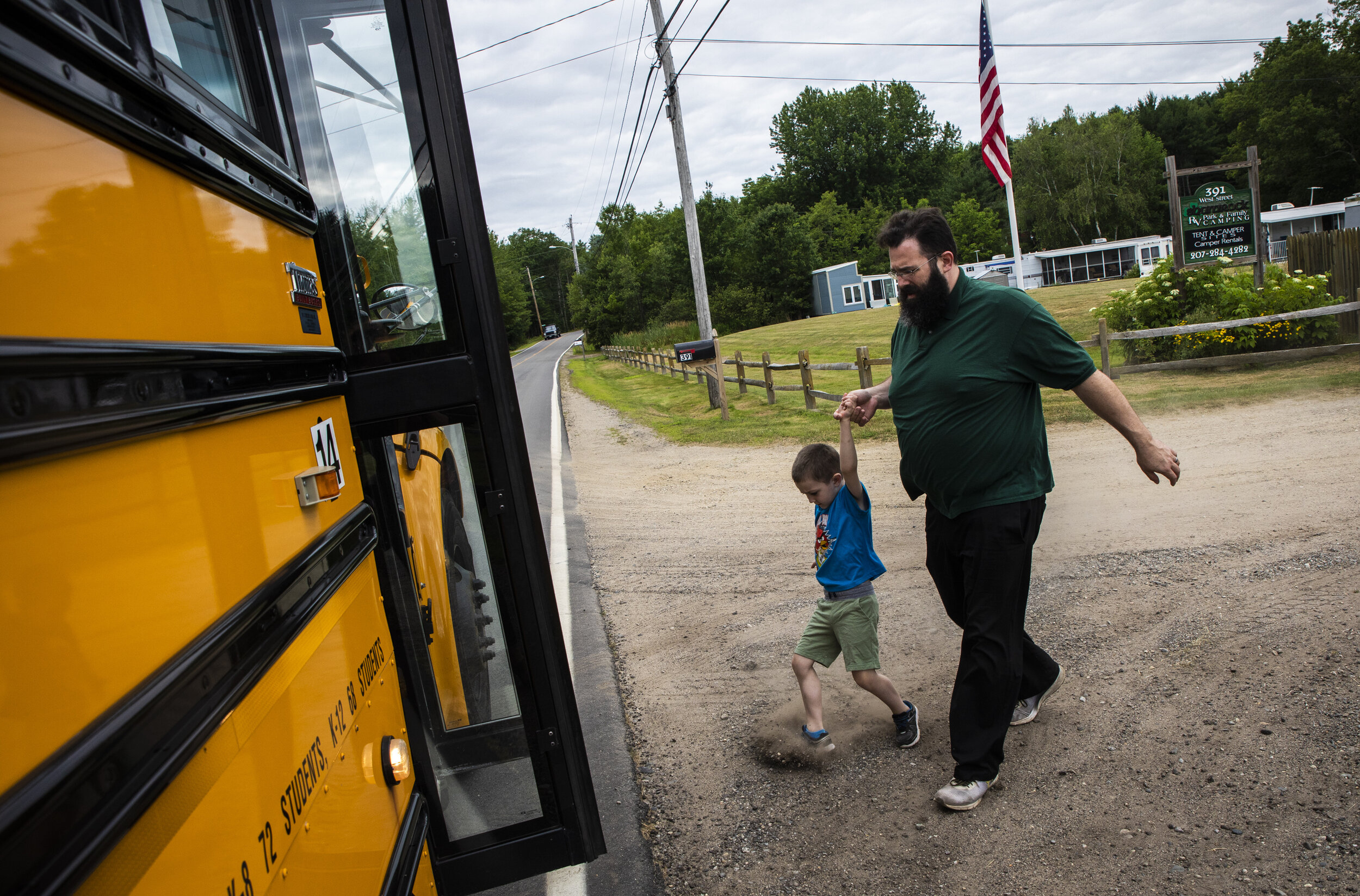 Dylan Lupien drags his feet while his father Patrick attempts to get him on the bus to summer school. The family made arrangements to have the children be picked up from the campground while they made