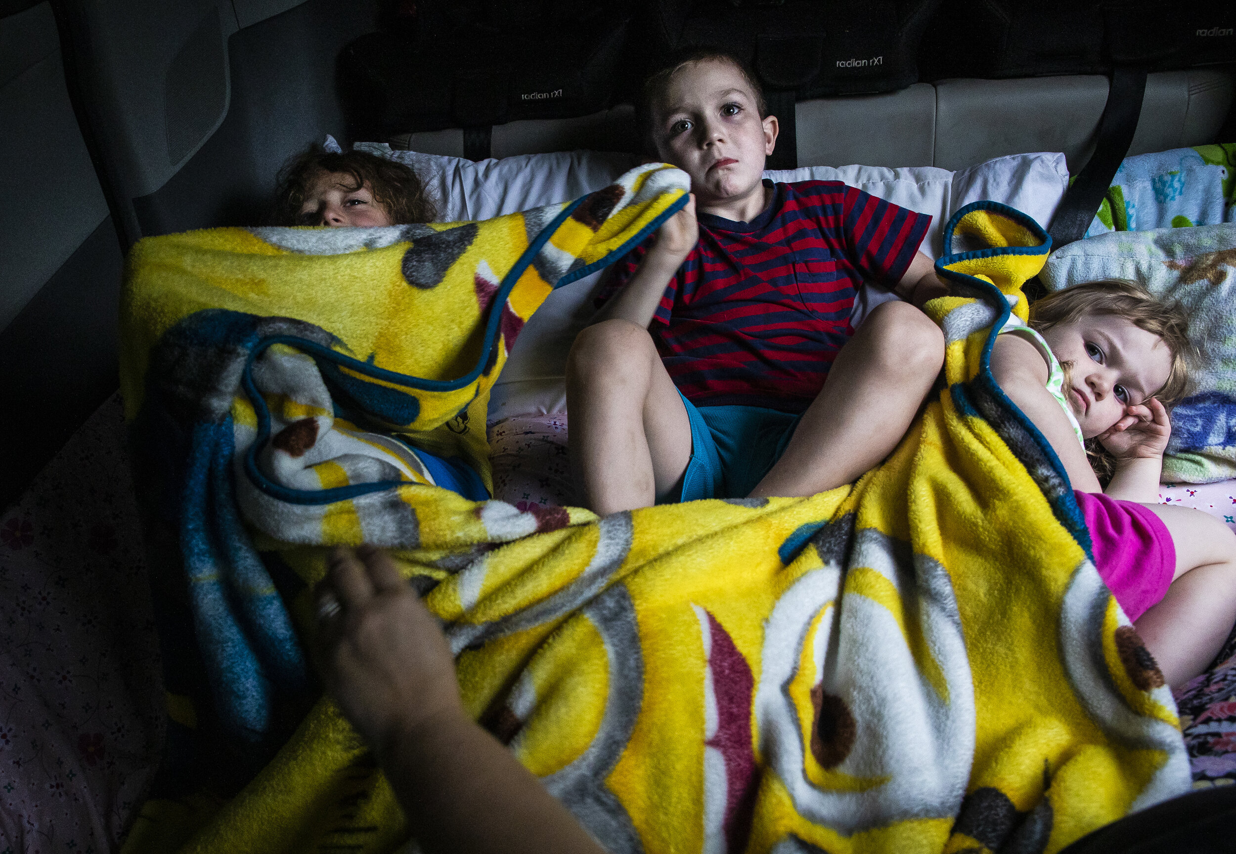 Siblings from left Evan,  Dylan and Laya watch a movie while getting ready for bed in the back of their family's van. After being evicted from their three bedroom apartment earlier that day, the Lupie