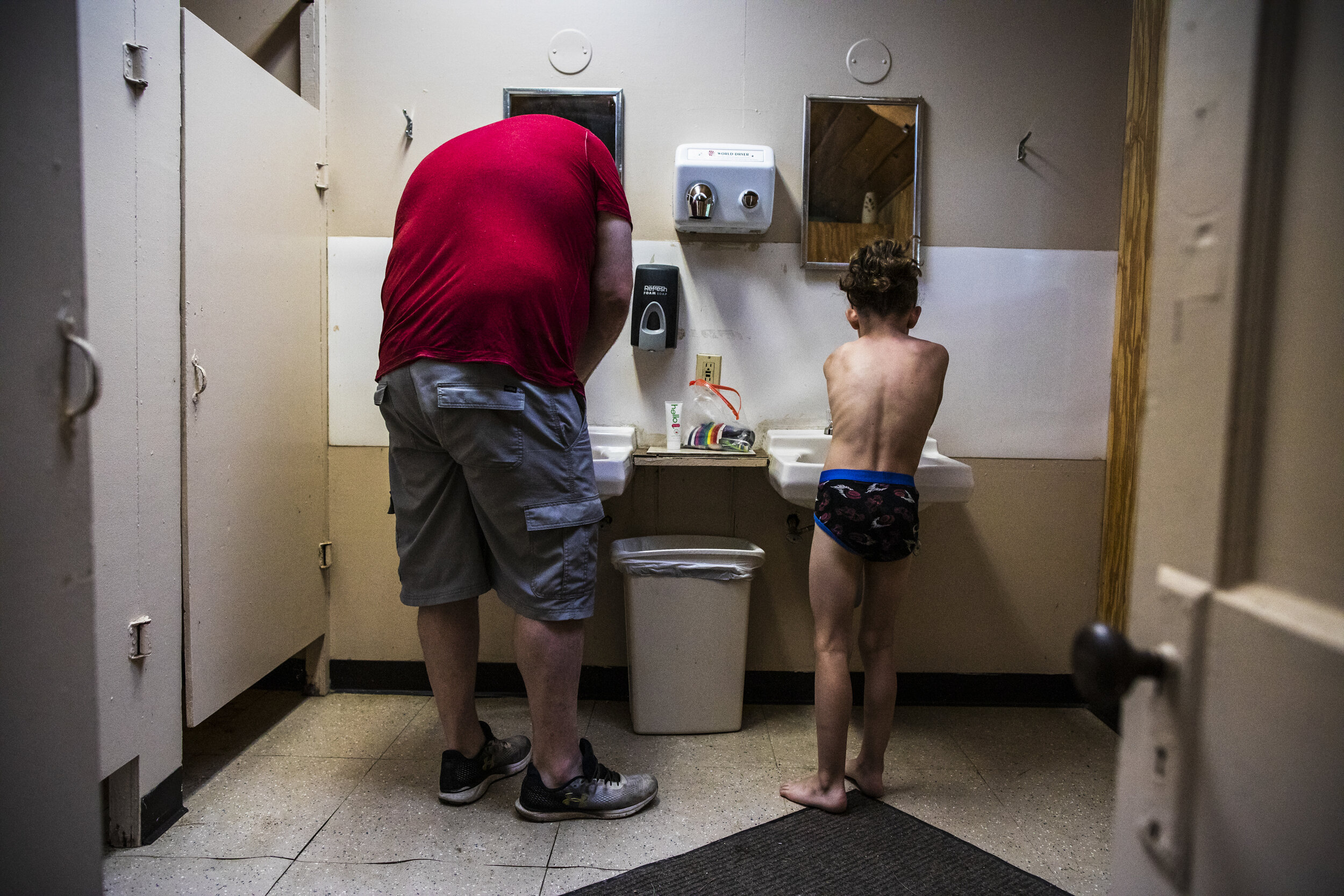 Patrick Lupien, left, brushes his teeth with his son Evan while they get ready for the day in the campground bathroom in the early hours of the morning. Campground life requires a very rigid schedule 