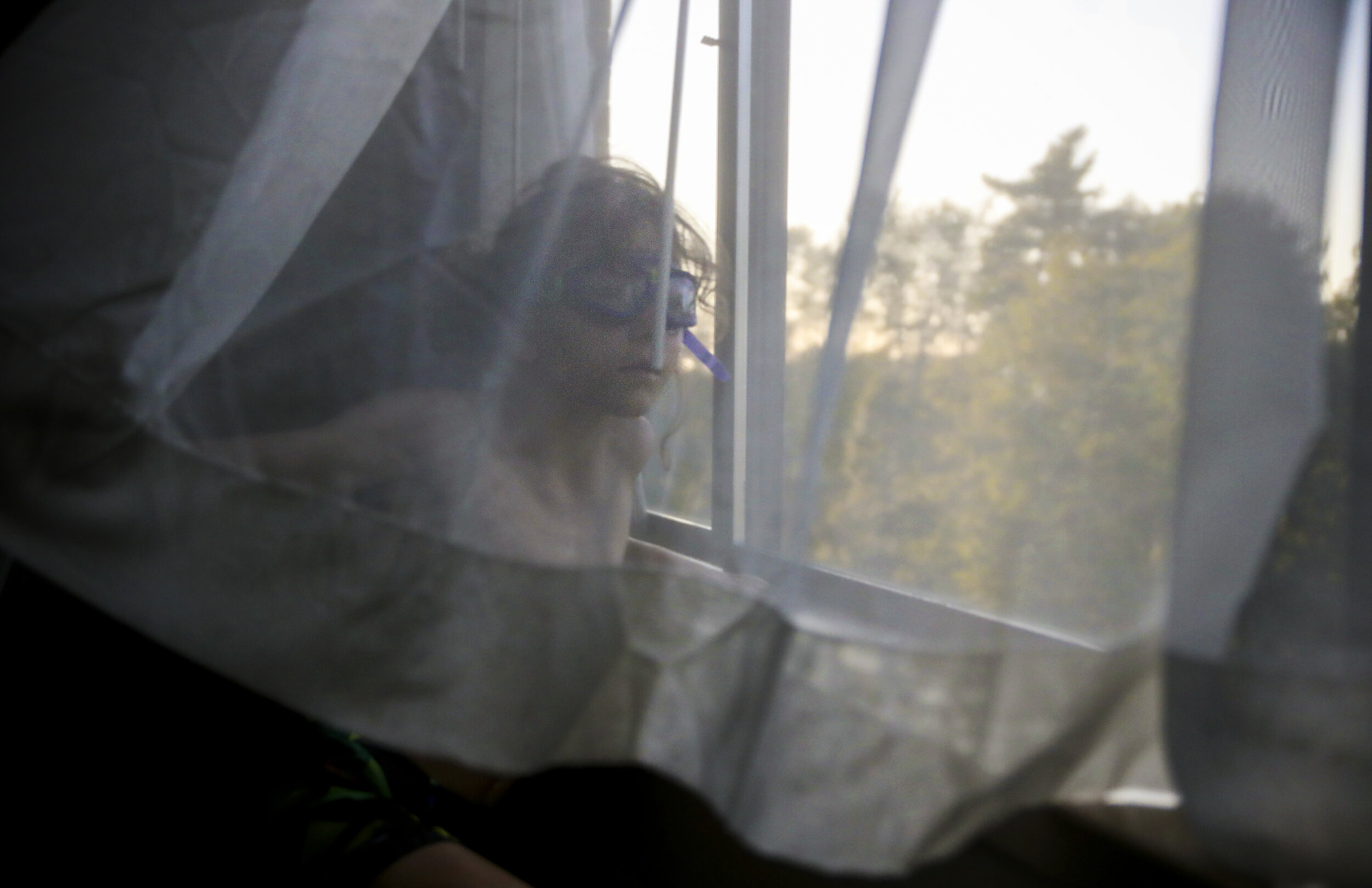 Evan Lupien peers out of the hotel window while wearing his goggles in preparation for a night of swimming. For the past month and a half, Evan and his family have been living in a campground after be