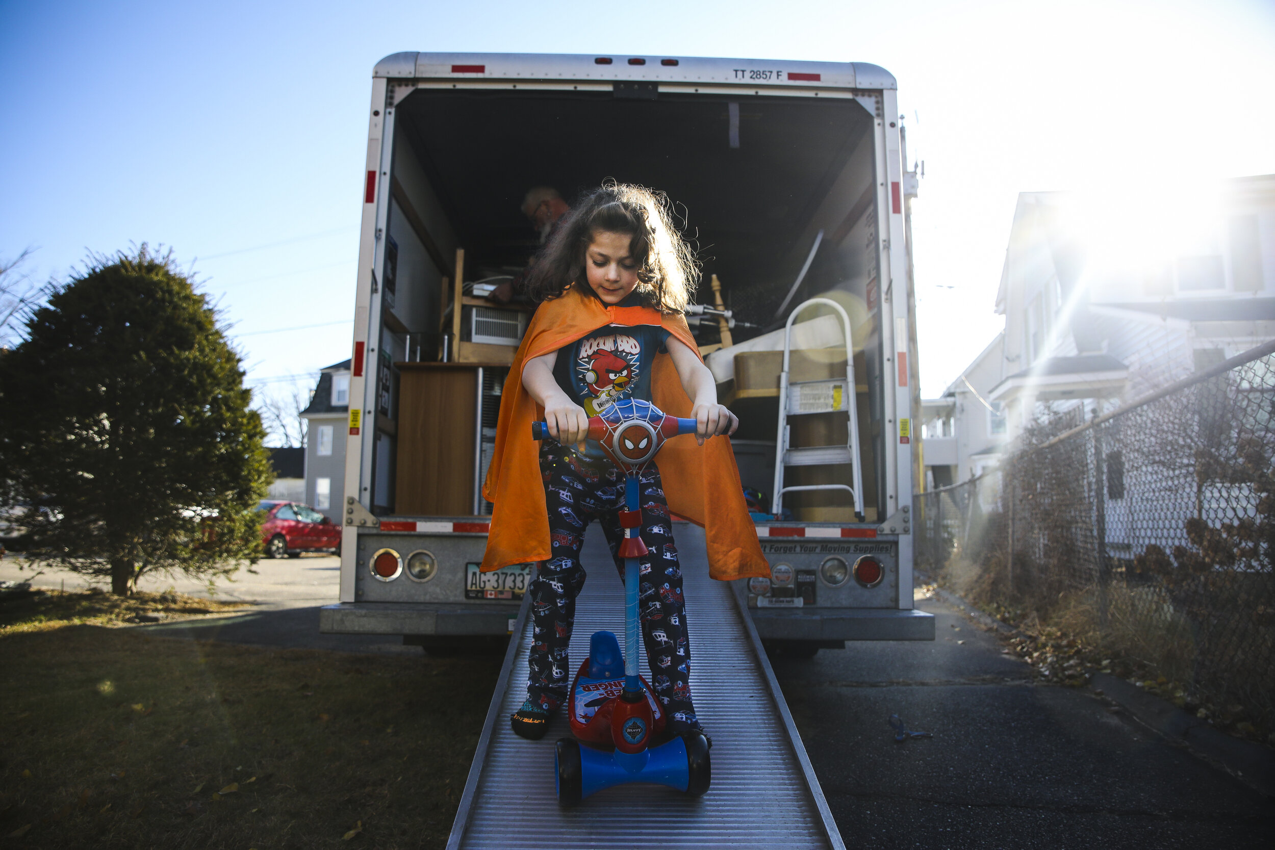 Evan Lupien rides his scooter down the ramp of the moving truck while friend's and family help the Lupiens move into their new apartment. The family has been homeless since July, with most of the chil