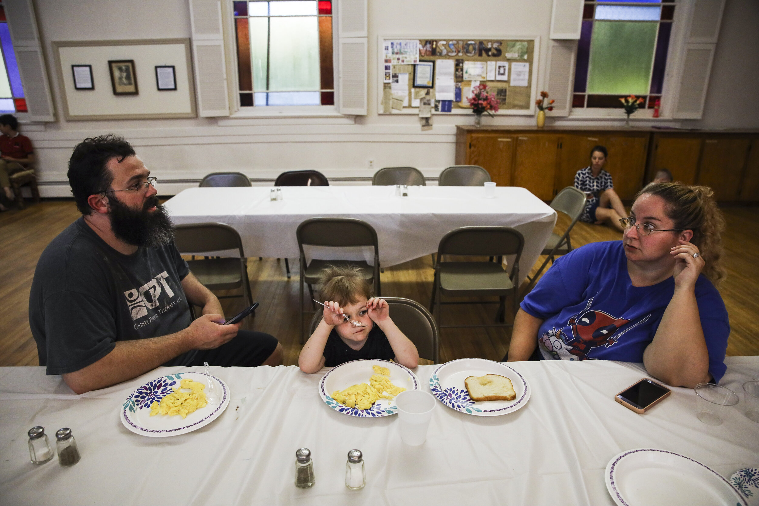 Patrick Lupien talks to his wife  Mariah LeMieux-Lupien while their daughter Laya eats dinner at the church where the family will be spending the night. In an effort to keep DHHS from taking their chi