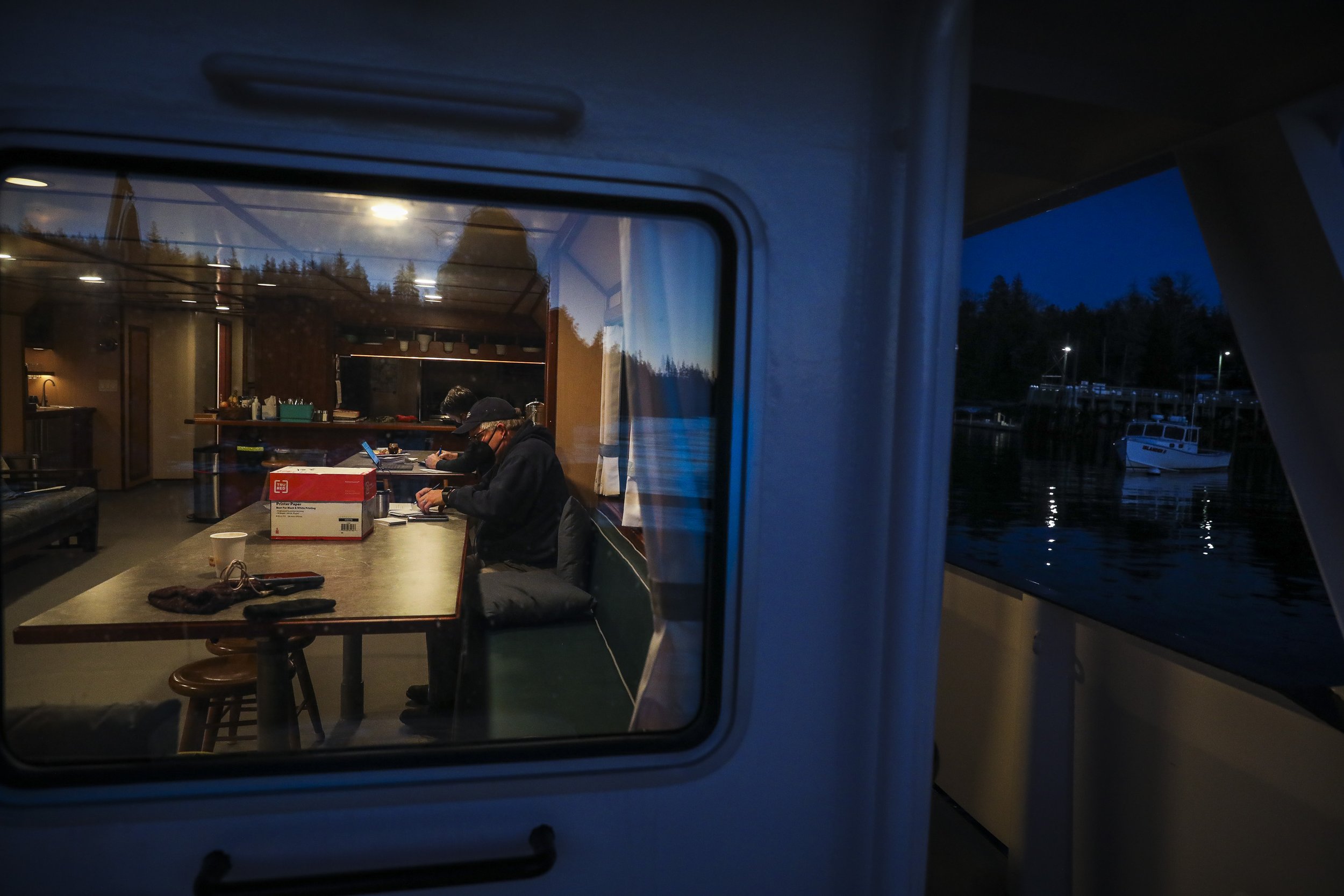  President of Seacoast Mission John Zavodny tallies the days vaccine totals as the Sunbeam arrives to Isle au Haut Harbor just before dark. After docking, the crew plans to sleep the night on the boat before beginning vaccinations on the island early