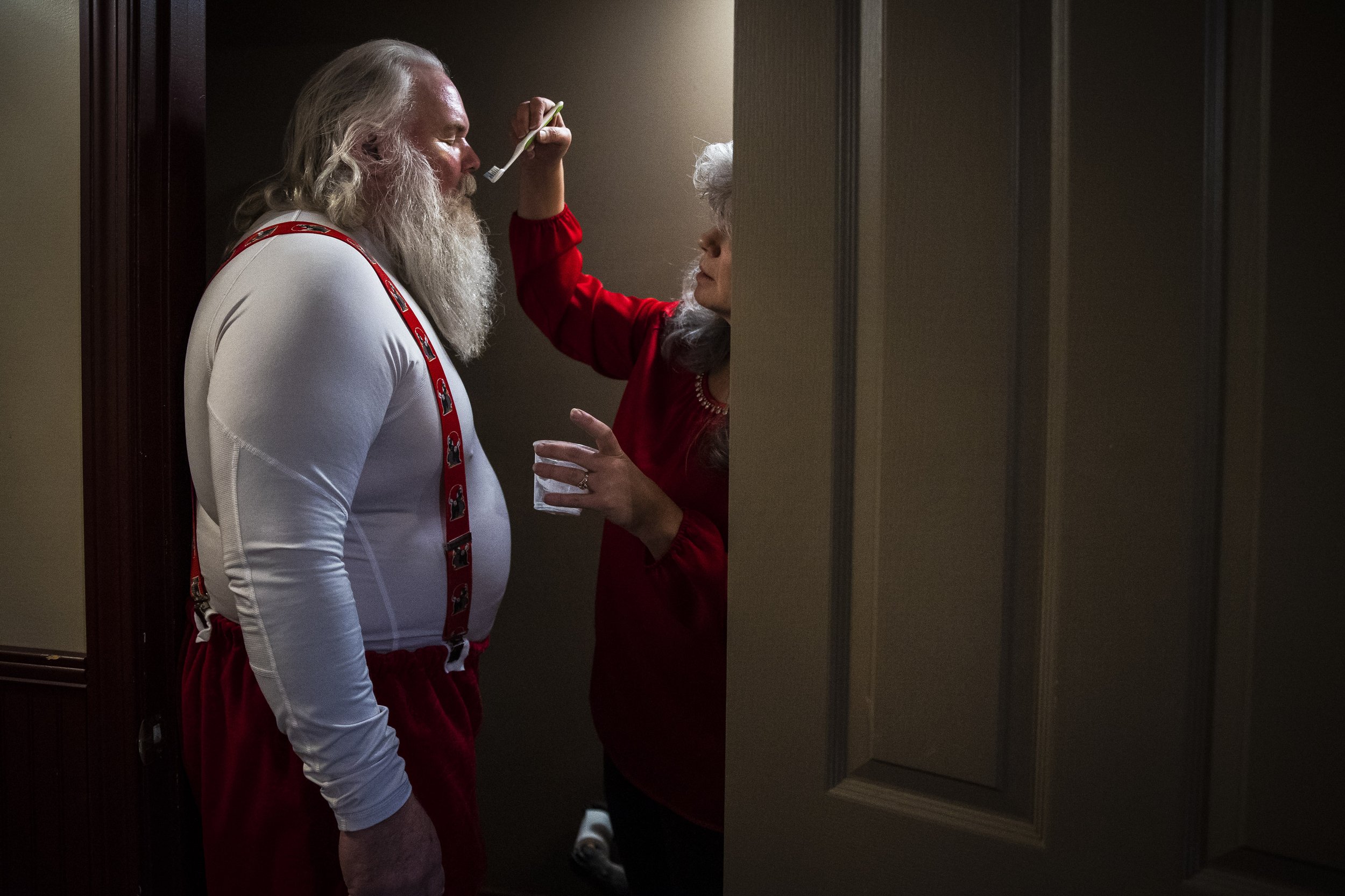  Rick Banks closes his eyes as his wife Anne uses a toothbrush to apply white theatre paint to his mustache on December 10, 2022. The Banks have always loved Christmas. When Rick ran multiple portrait studios across the state, he would watch the mall