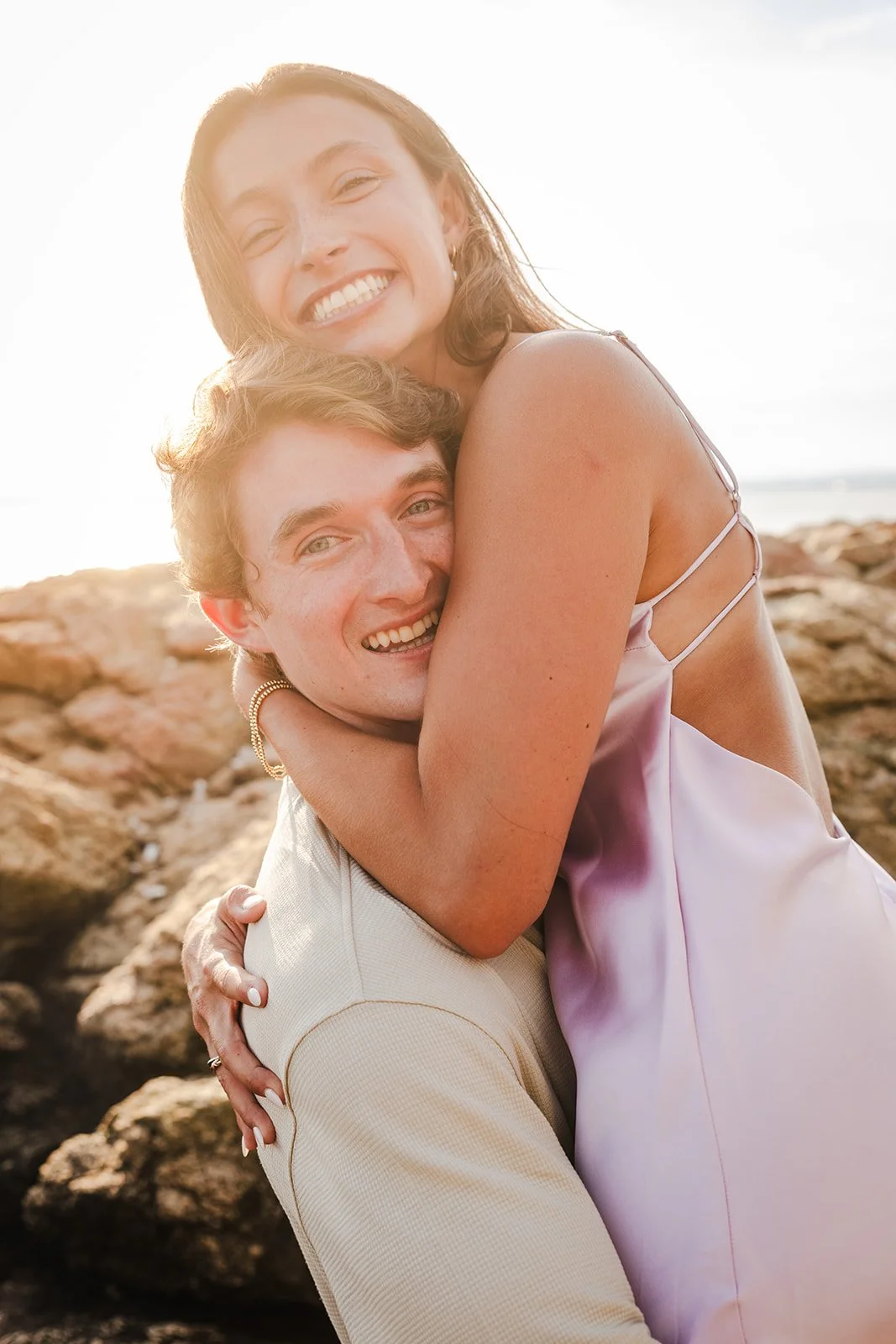 A newly engaged couple hugging in Lighthouse Point Park near New Haven, CT.