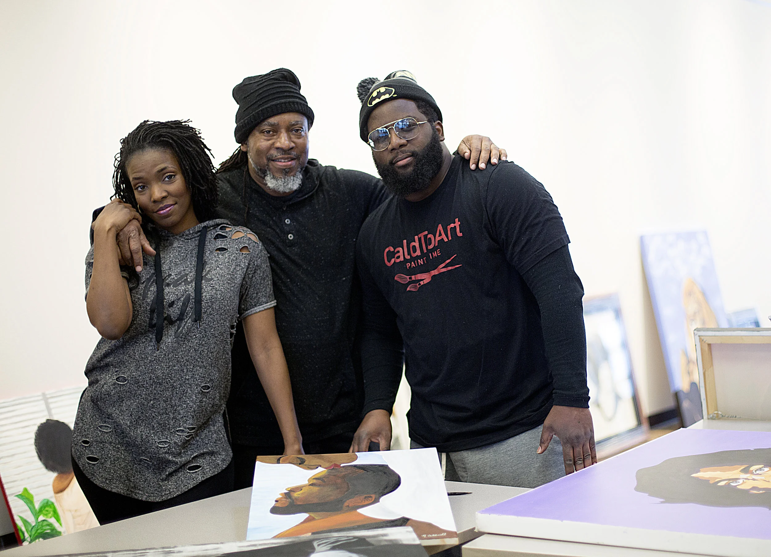 Charles Caldwell (center) and his children, Nakesha (left) and Kenneth (right) pose amidst their paintings as they hung their Black History Month art show at UROC.