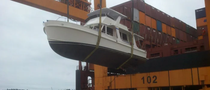 A Grand Banks yacht being offloaded from a shipping vessel.