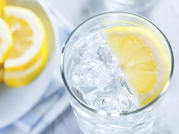 Glass of water with slice of lemon and ice (Source: sharecare )