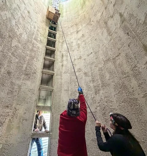 Volunteers hoist a barn owl box to the top of a silo using a pulley system. Photo by Margaret Poethig.