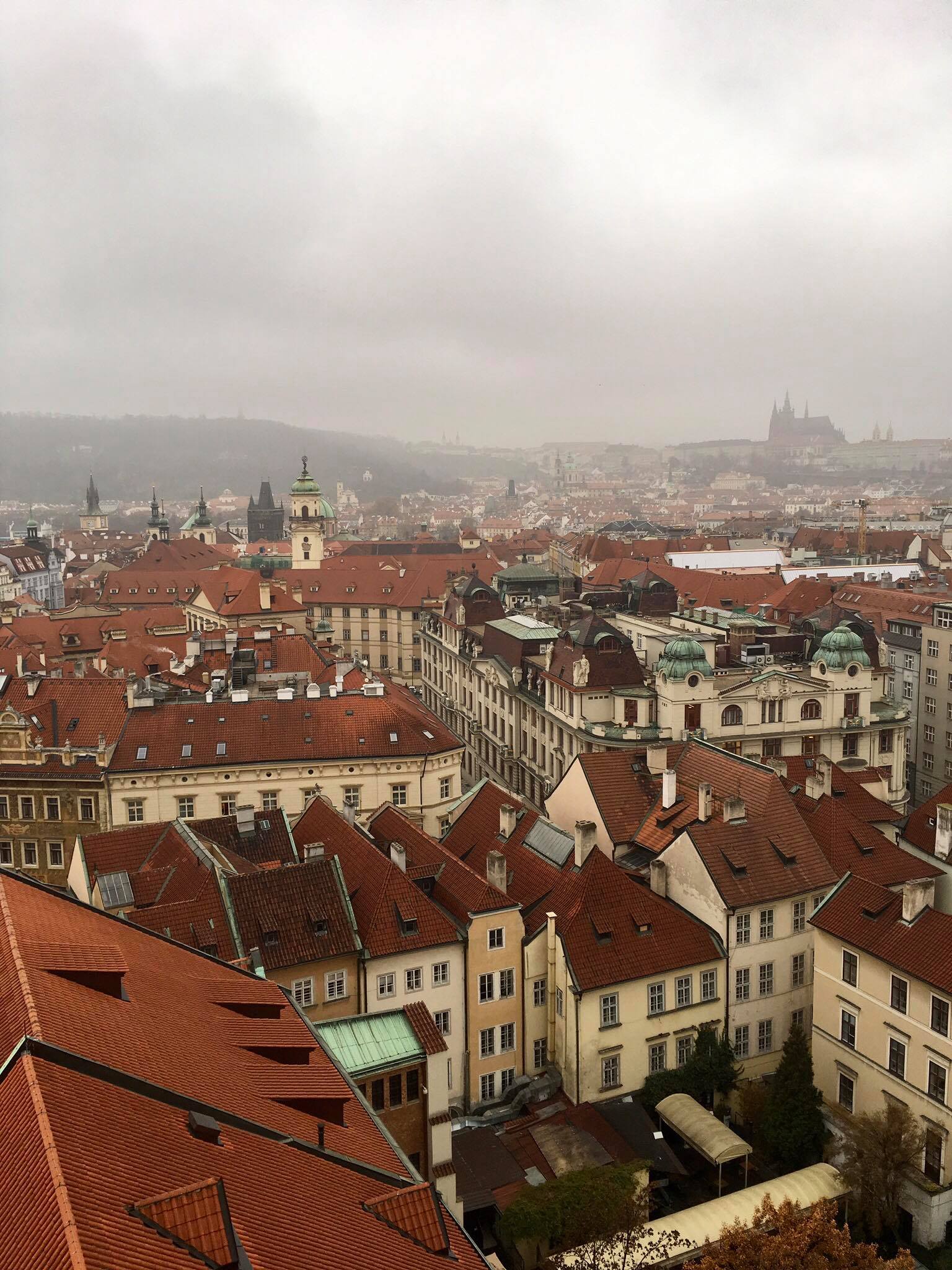 Old town, with an outline of the Prague Castle in the foggy distance. 