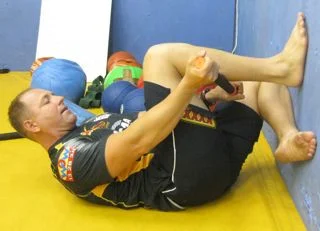 Using the Tiger Tail to roll the calves in a flexed knee closed kinetic chain position