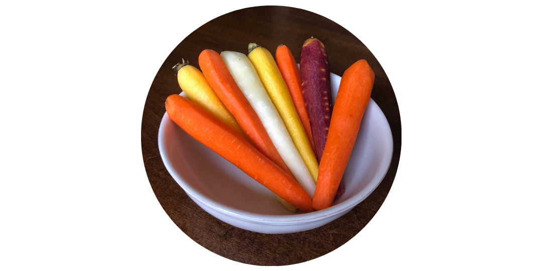 Multiple colors of carrots in a white ceramic bowl