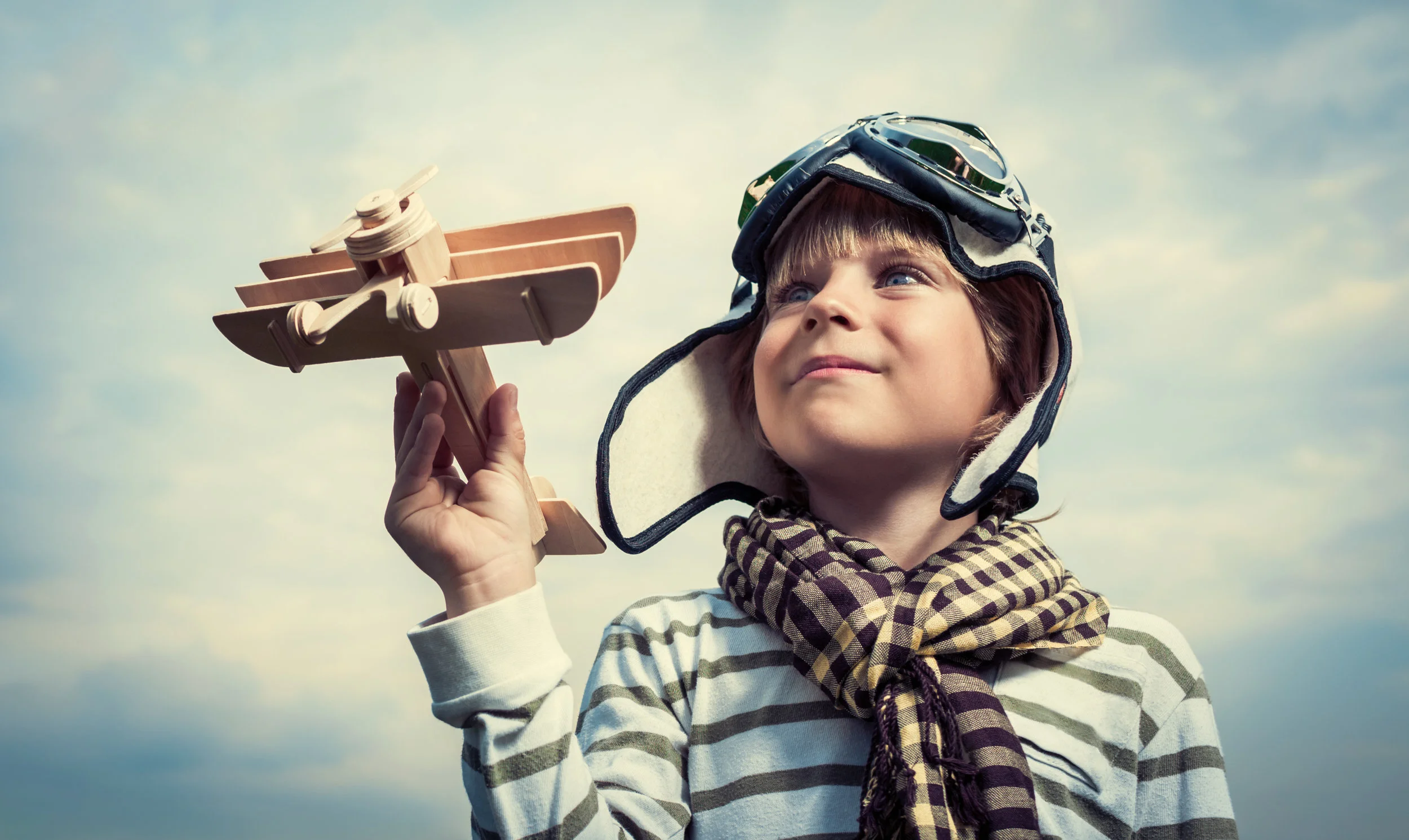 Boy dreaming of flying with wooden airplane