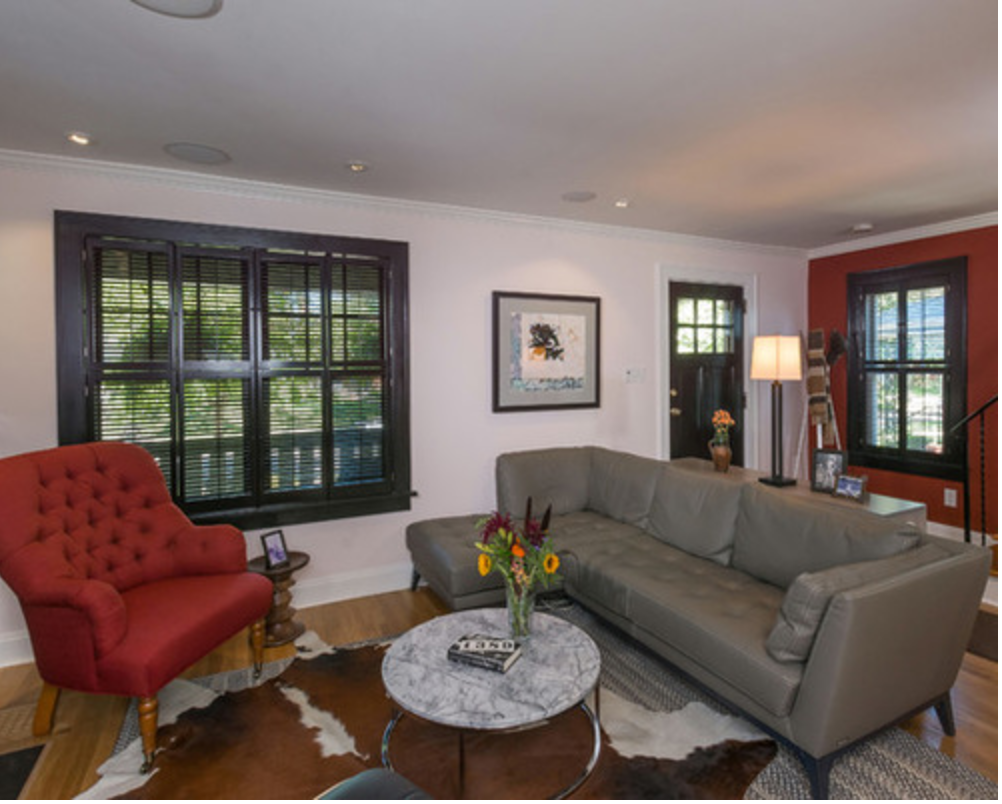 The tufted, red chair carries that color further into the room from the opposite staircase wall. Repeating details like the layered rugs and cabinetry/millwork help make different functional spaces feel like one cohesive space.