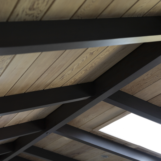 Vaulted ceiling with tongue and groove natural wood planks, and boxed beams in dark stained wood.