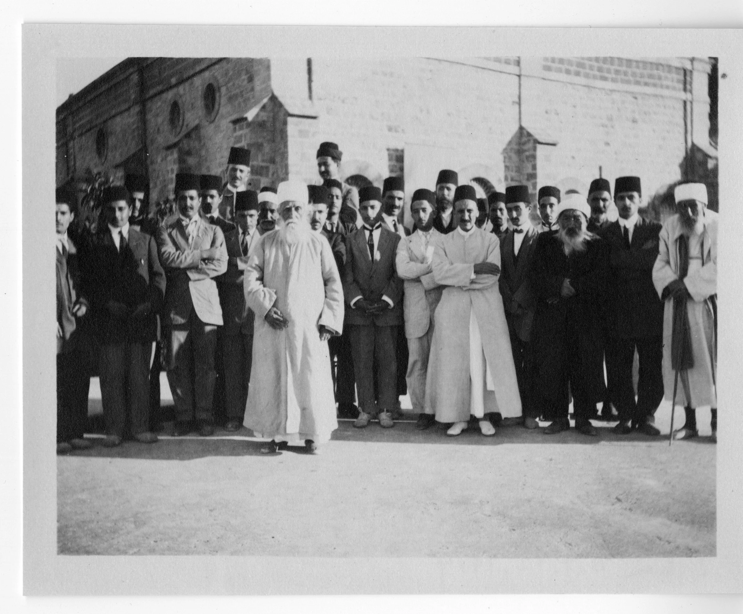 The Master with Baha'is at the northwest corrner of the Shrine of the Bab. Note the father of Shoghi Effendi, Mirza Hadi Shirazi, in front row wearing white gown and with arms folded. Third from right is 'Abbas-Quli of Qom, whom 'Abdu'l-Baha had appointed custodian of the Shrine. 