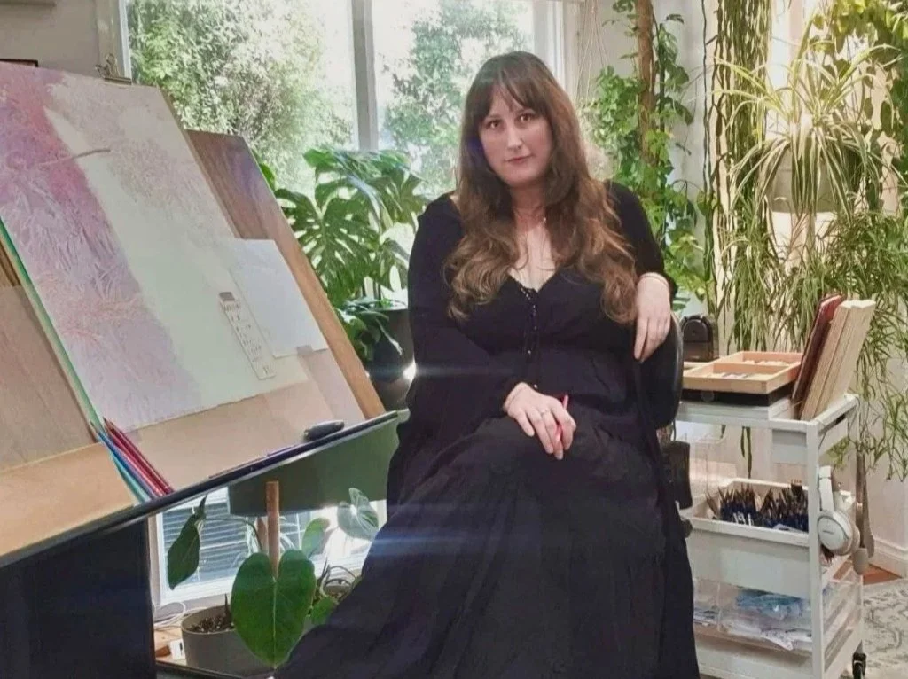 Artist Becc Orszag in her art studio withe a drawing in progress on an easel