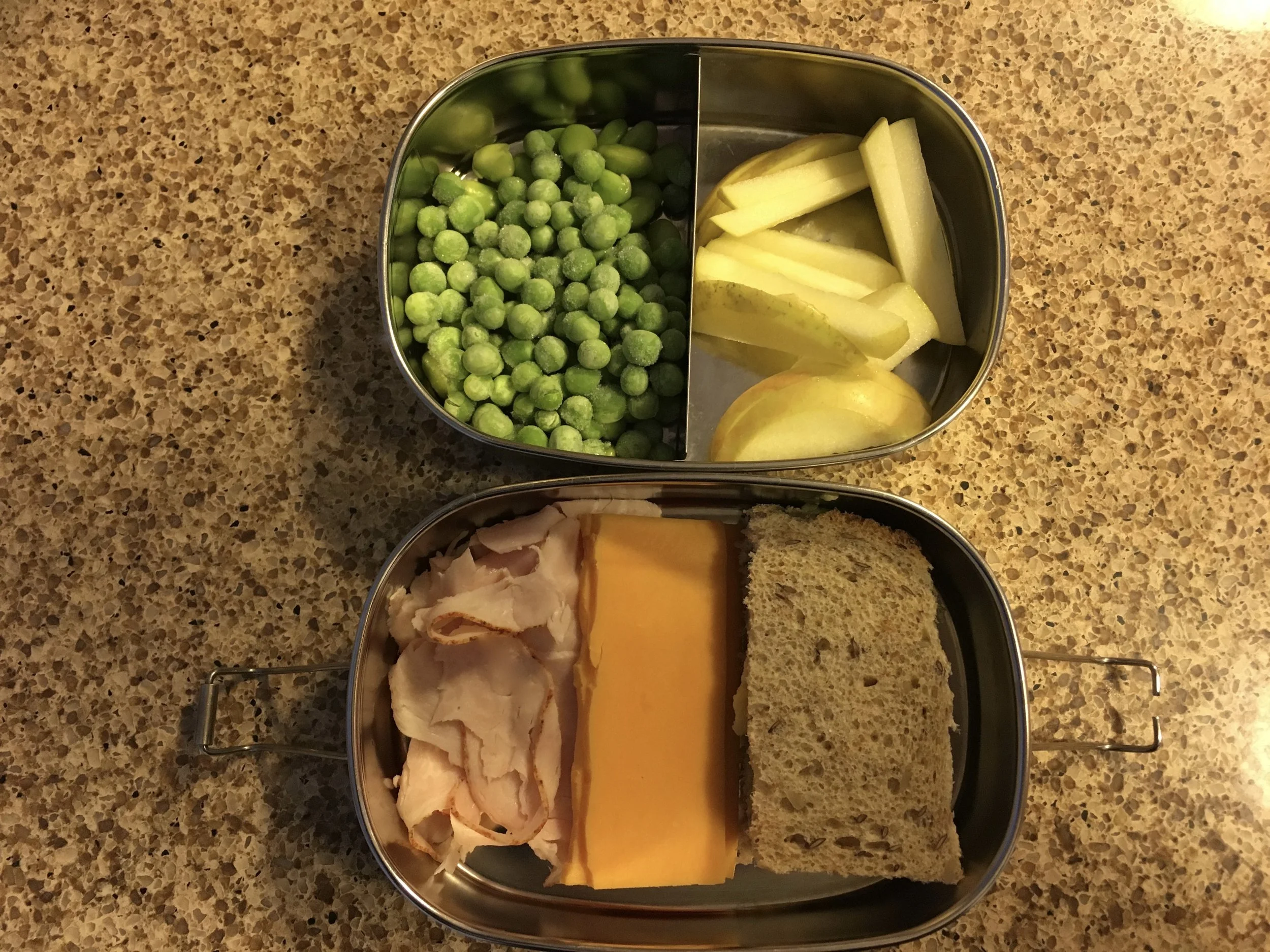 Super simple lunch. Clockwise from top left: frozen peas, sliced apple, bread, cheese and turkey