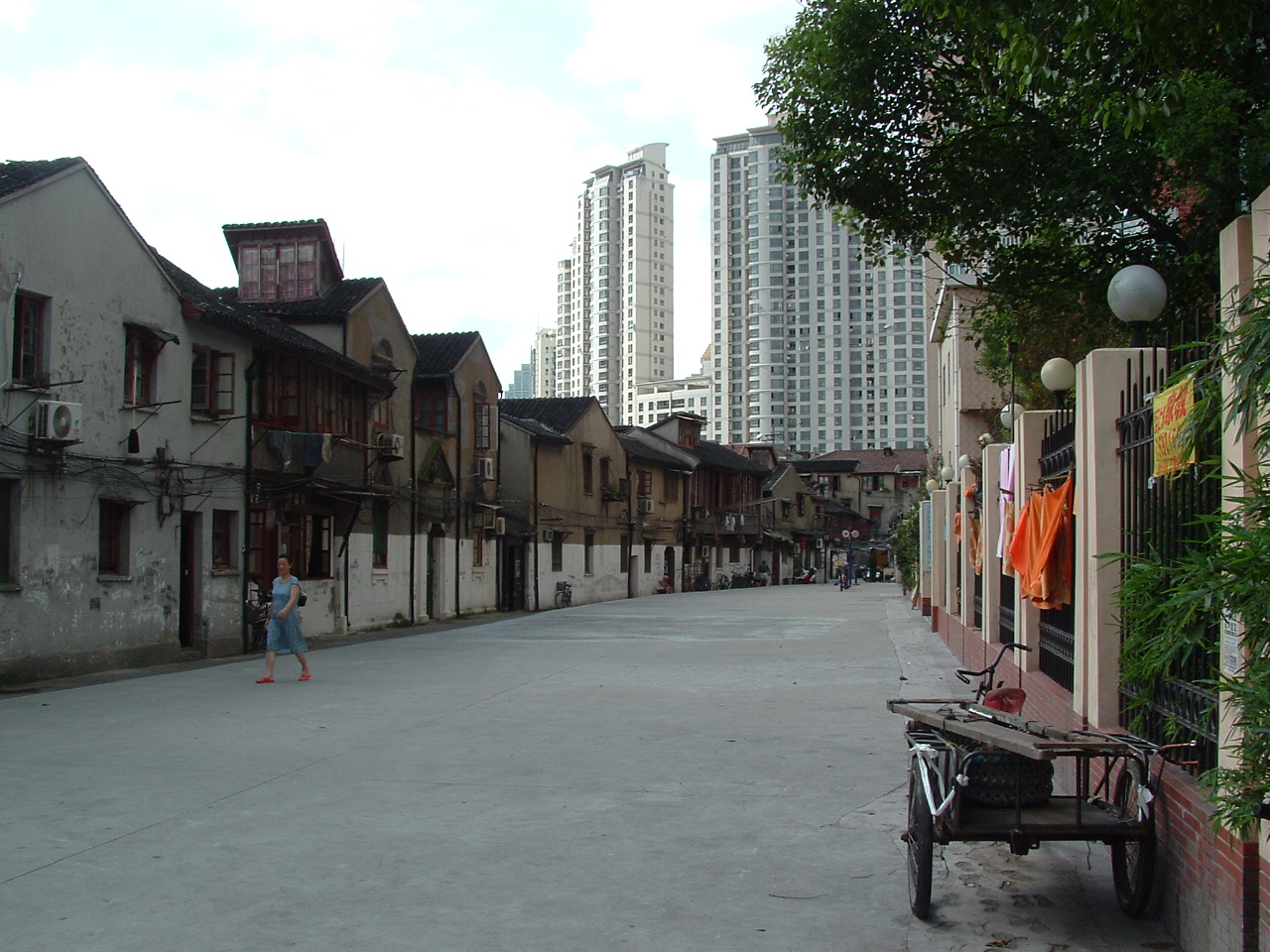 An old Hutong-style roadway in Shanghai, contrasting with high-rise apartments towering behind.