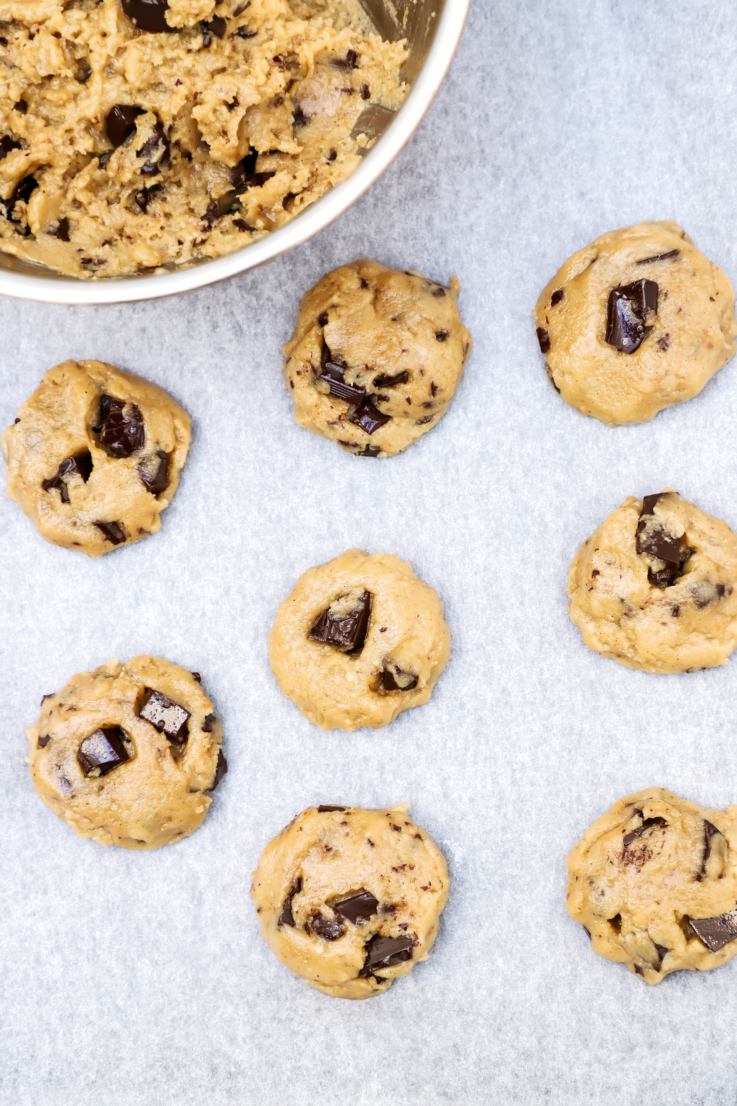 vegan and gluten-free chocolate chip cookie dough scooped out and placed on a baking sheet