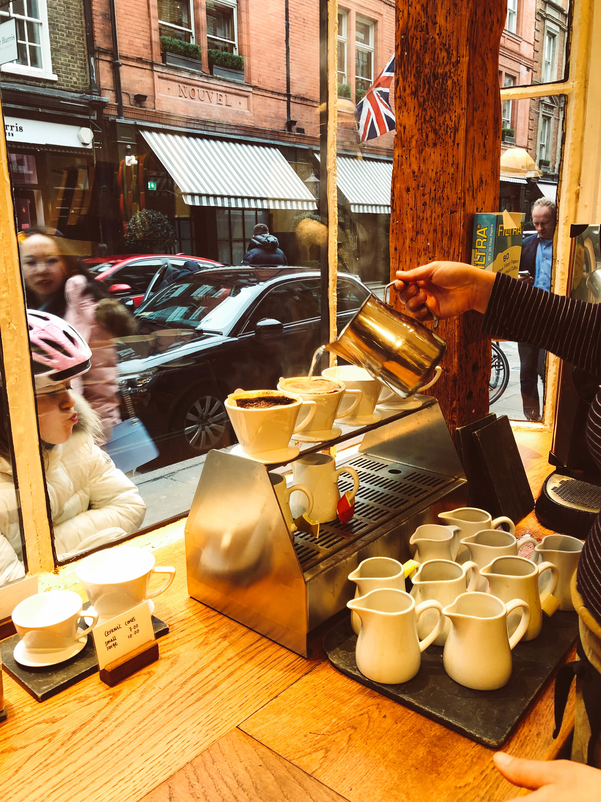 Monmouth Coffee London - pour over coffee being made in the window with pitchers of samples below