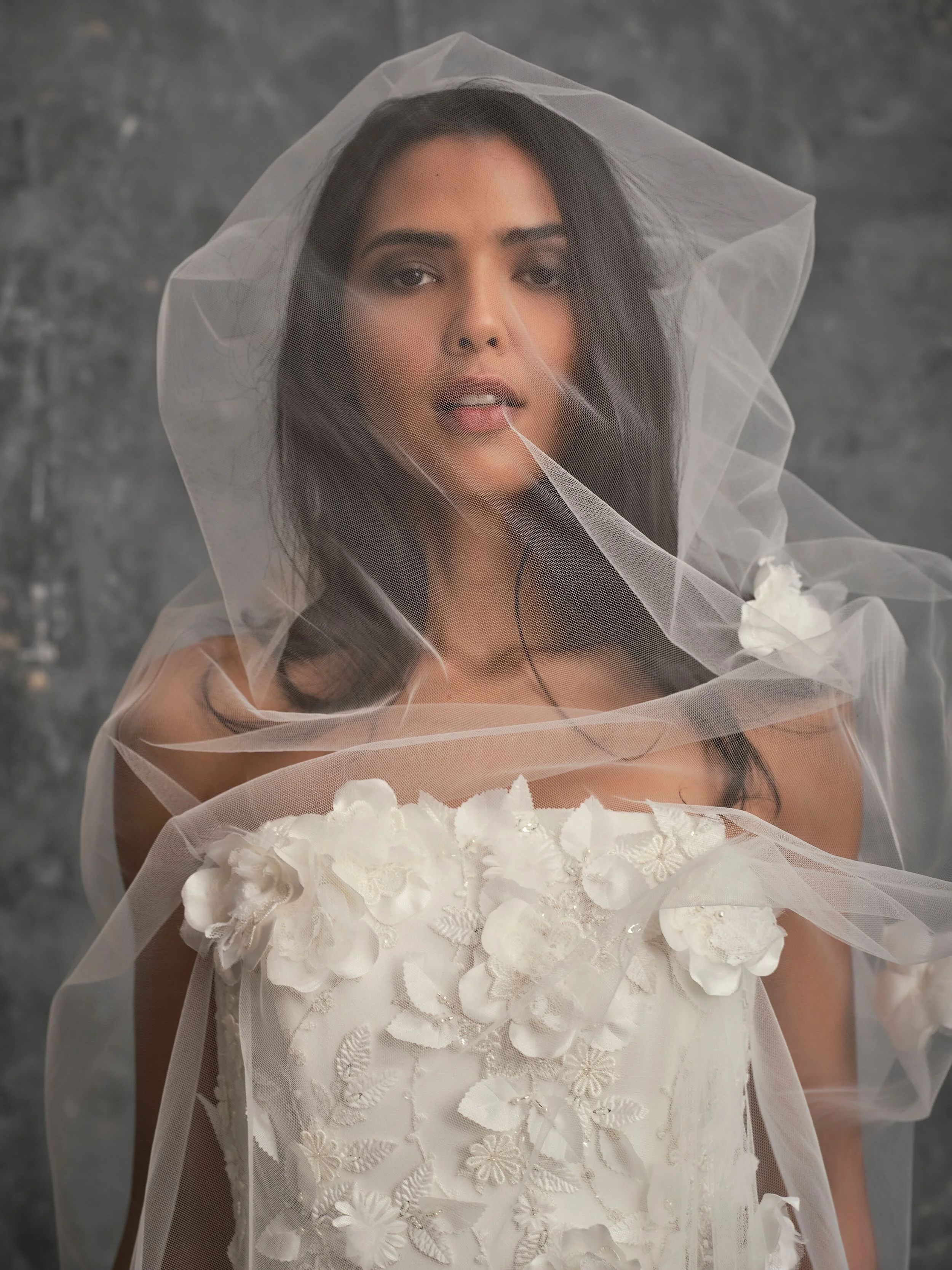 Close-up of 3D floral wedding dress bodice with couture floral appliqués and delicate bridal veil