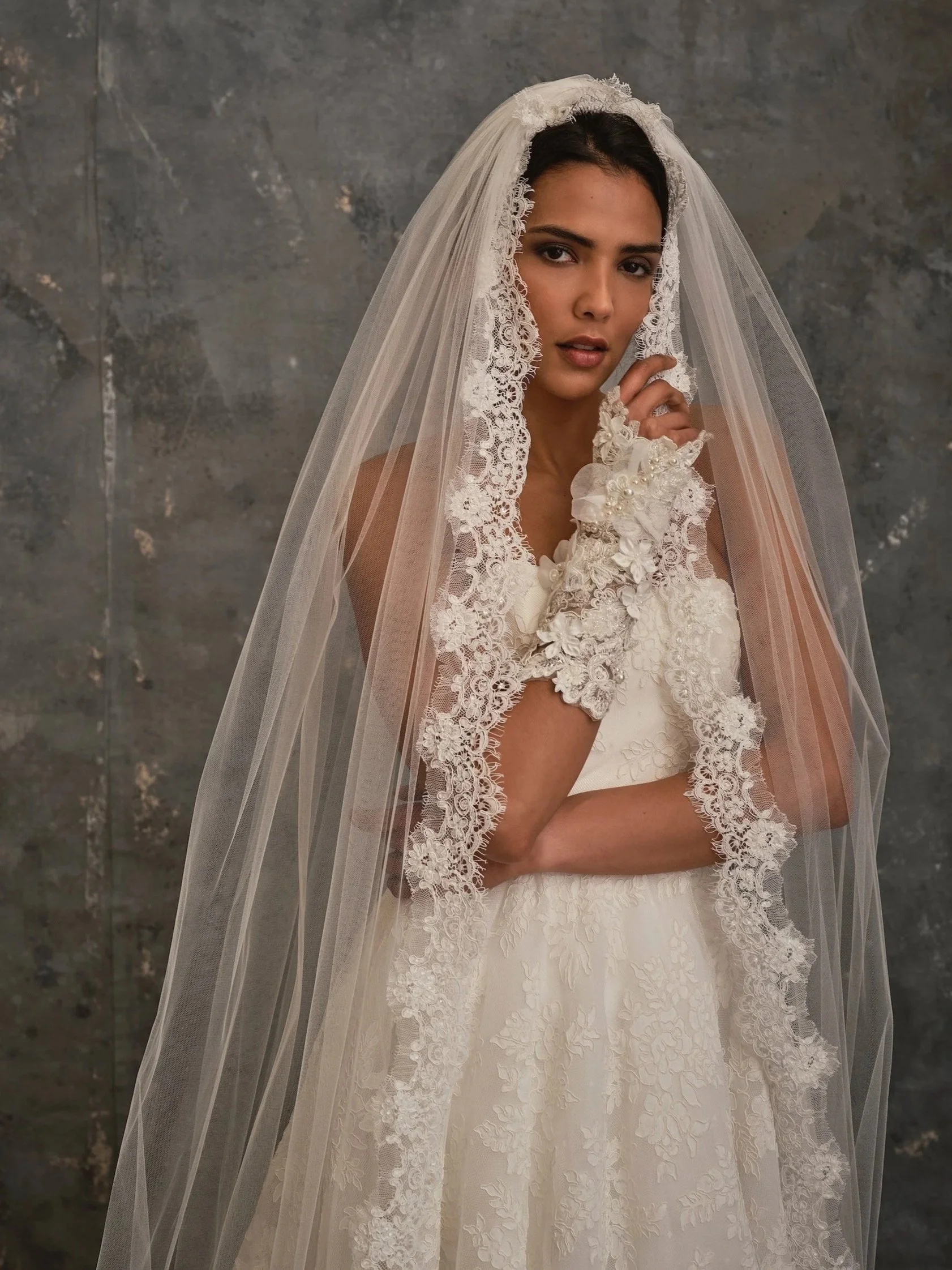 Bride wearing lace wedding dress with lace edged cathedral veil and lace gloves