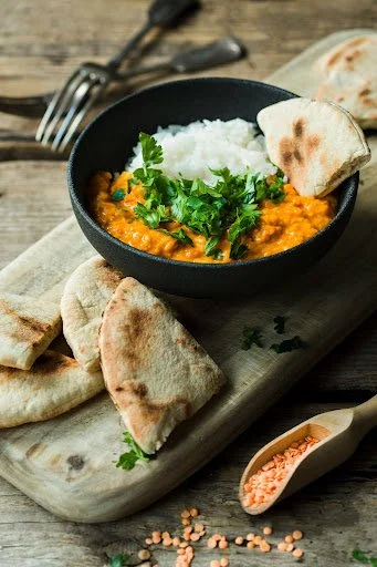 black bowl with white rice and red lintel dal